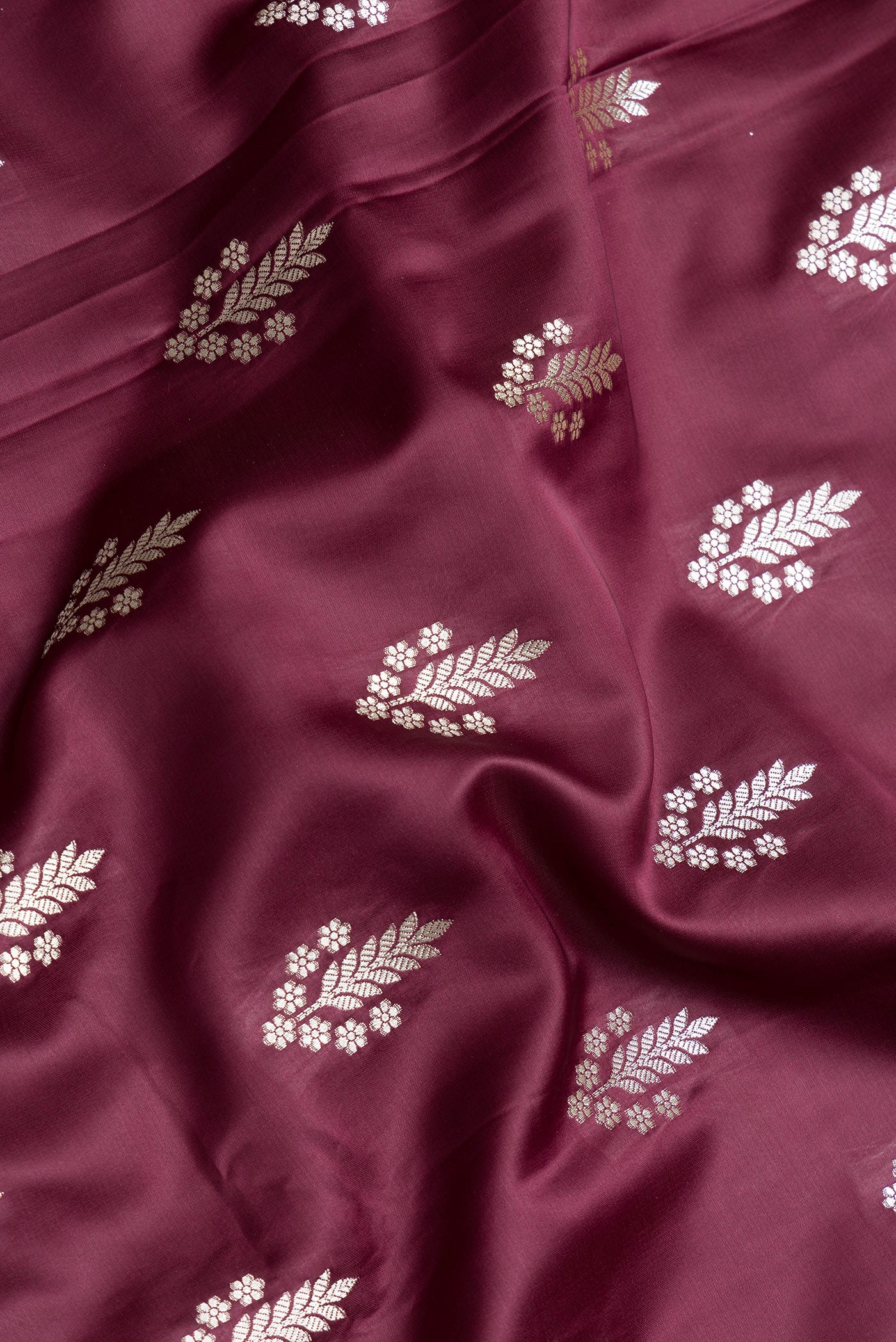 Close up of Maroon Dual Tone Banarasi Silk Saree with Zari Butta on the body and Zari Border.  displaying folds