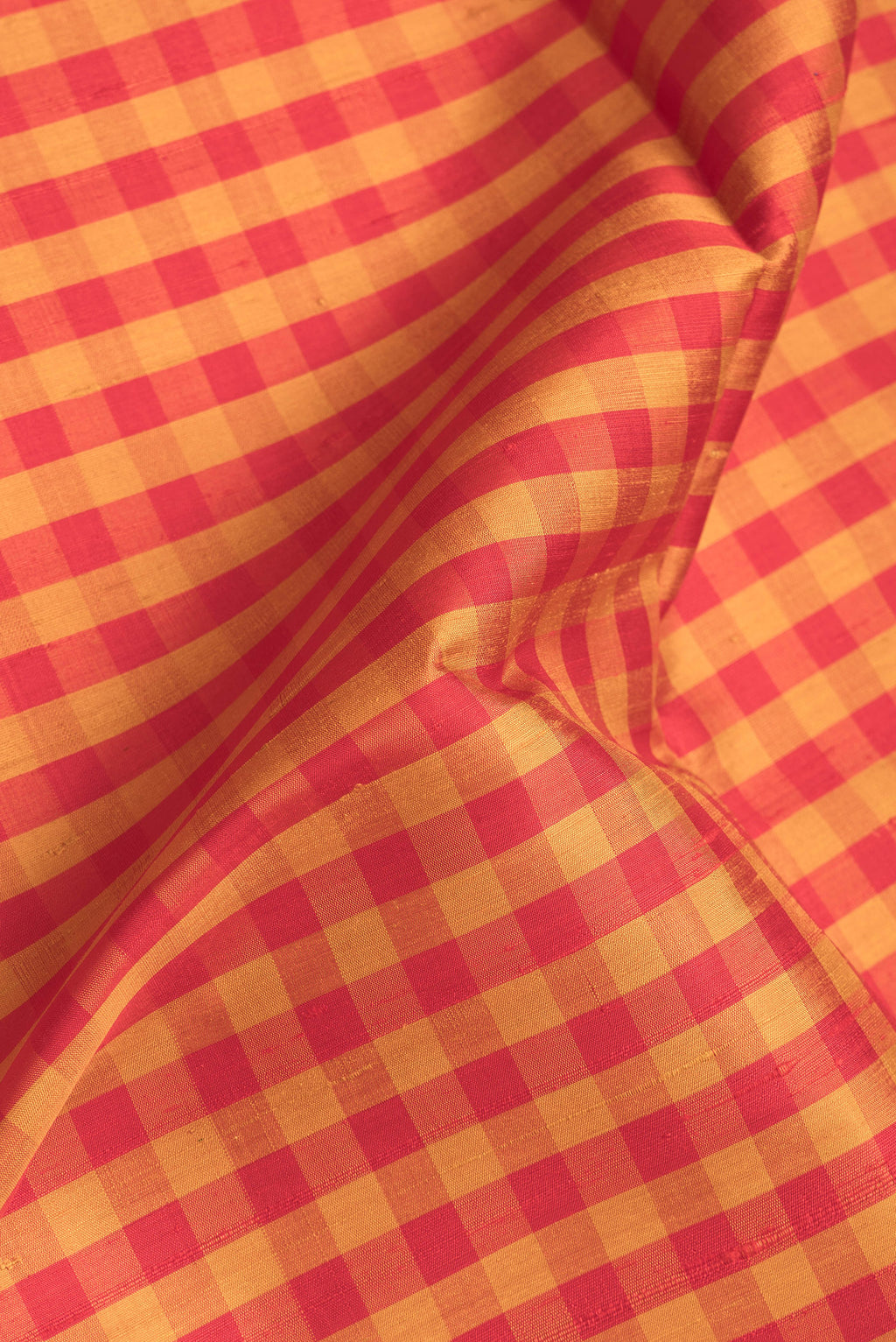 Close up of Red and Mustard Color Raw Silk Saree with Checked design on the body and Thin Zari Line.  displaying folds