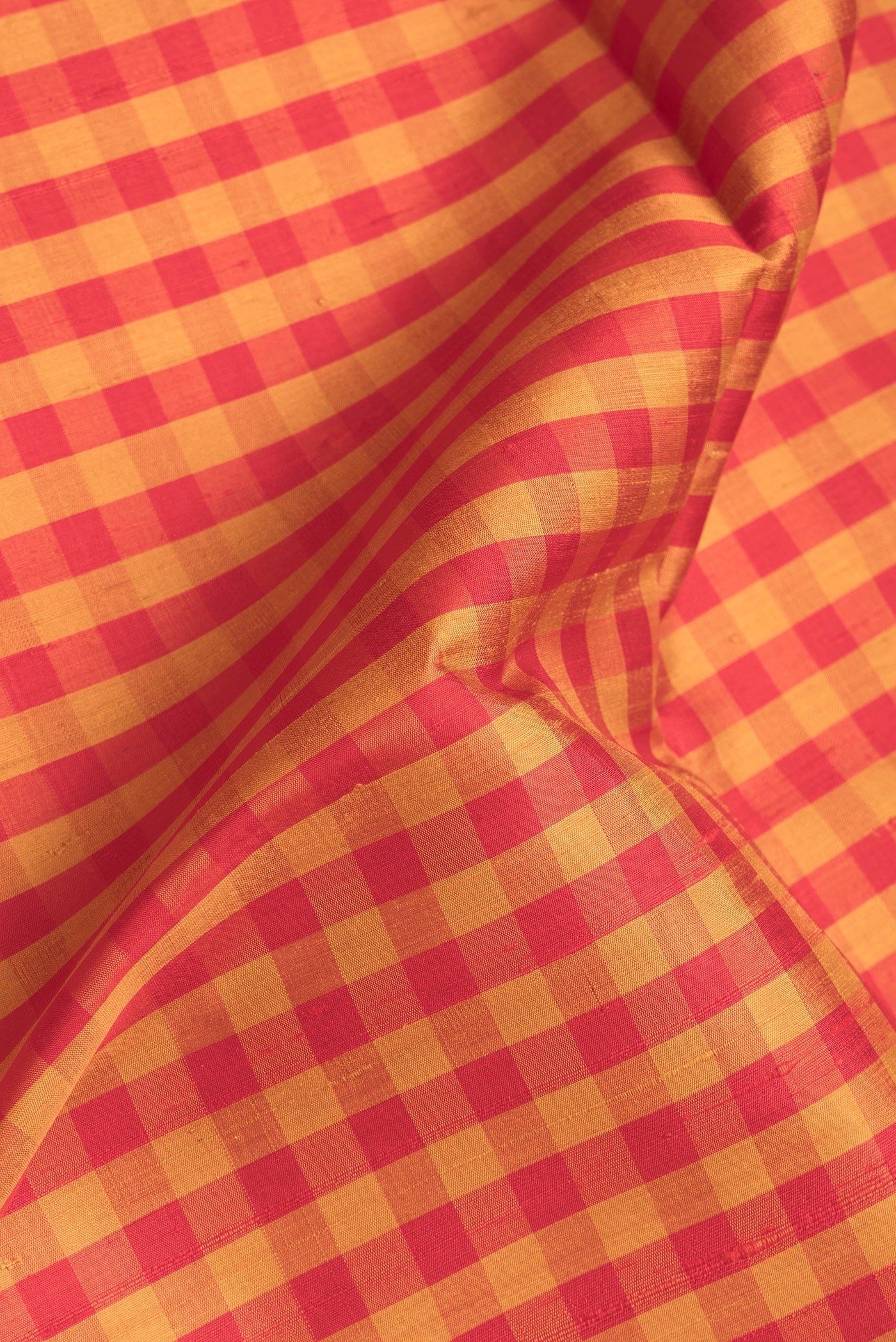 Close up of Red and Mustard Color Raw Silk Saree with Checked design on the body and Thin Zari Line.  displaying folds