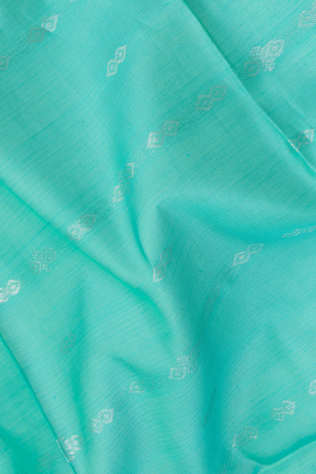 Close up of Sea Green Silk Cotton Saree with Zari Butta on the body and Zari Border.  displaying folds