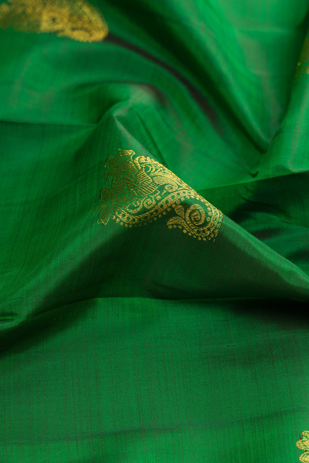 Close up of Green Dual Tone Kanchipuram Silk Saree with Zari Butta on the body and Zari Border.  displaying folds