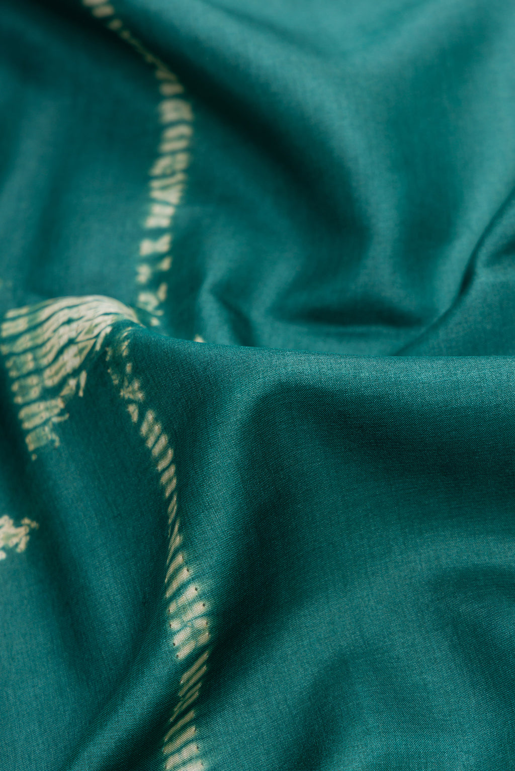 Close up of Green Dual Tone Tussar Silk Saree with Printed design on the body and Embroidery Border.  displaying folds