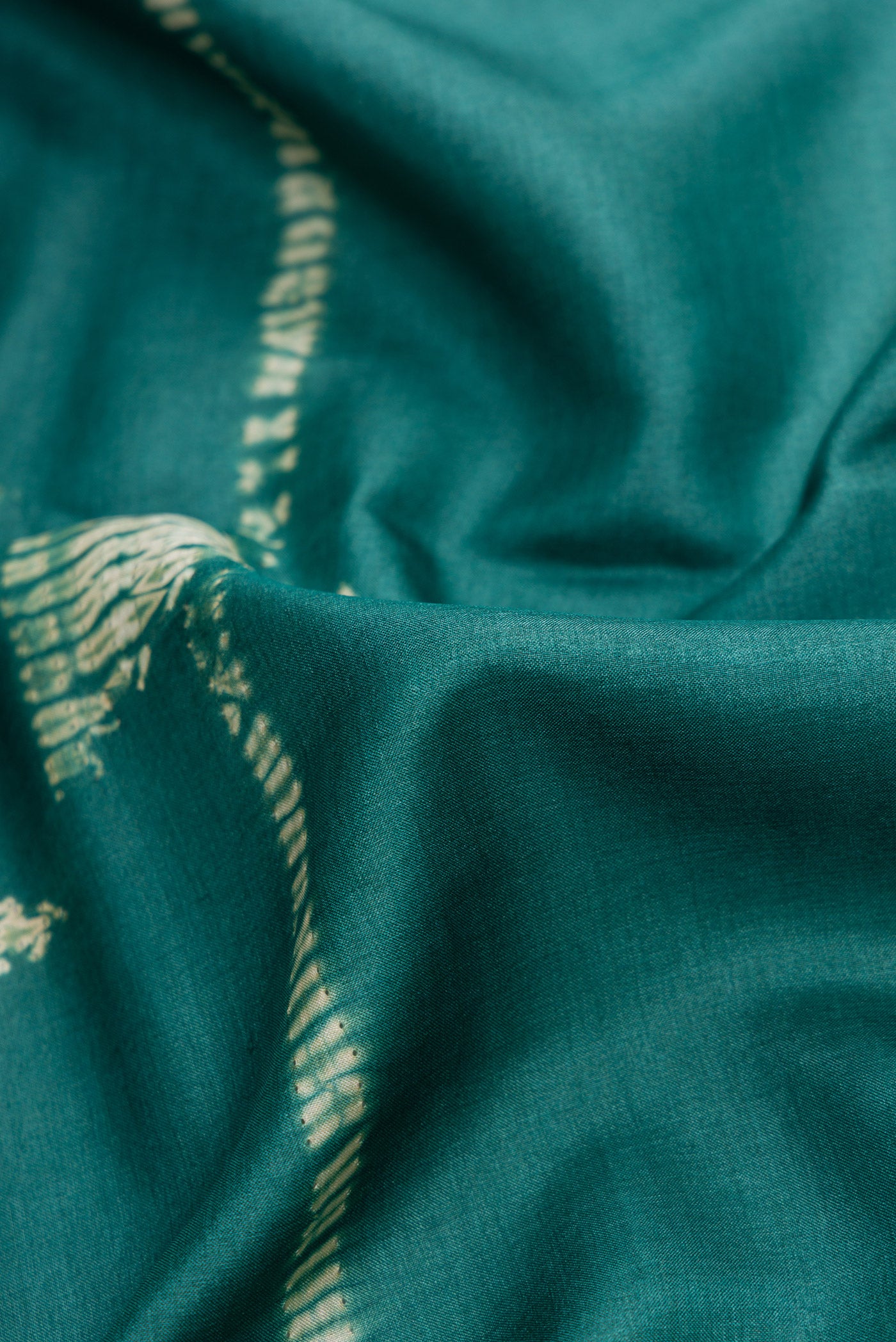 Close up of Green Dual Tone Tussar Silk Saree with Printed design on the body and Embroidery Border.  displaying folds