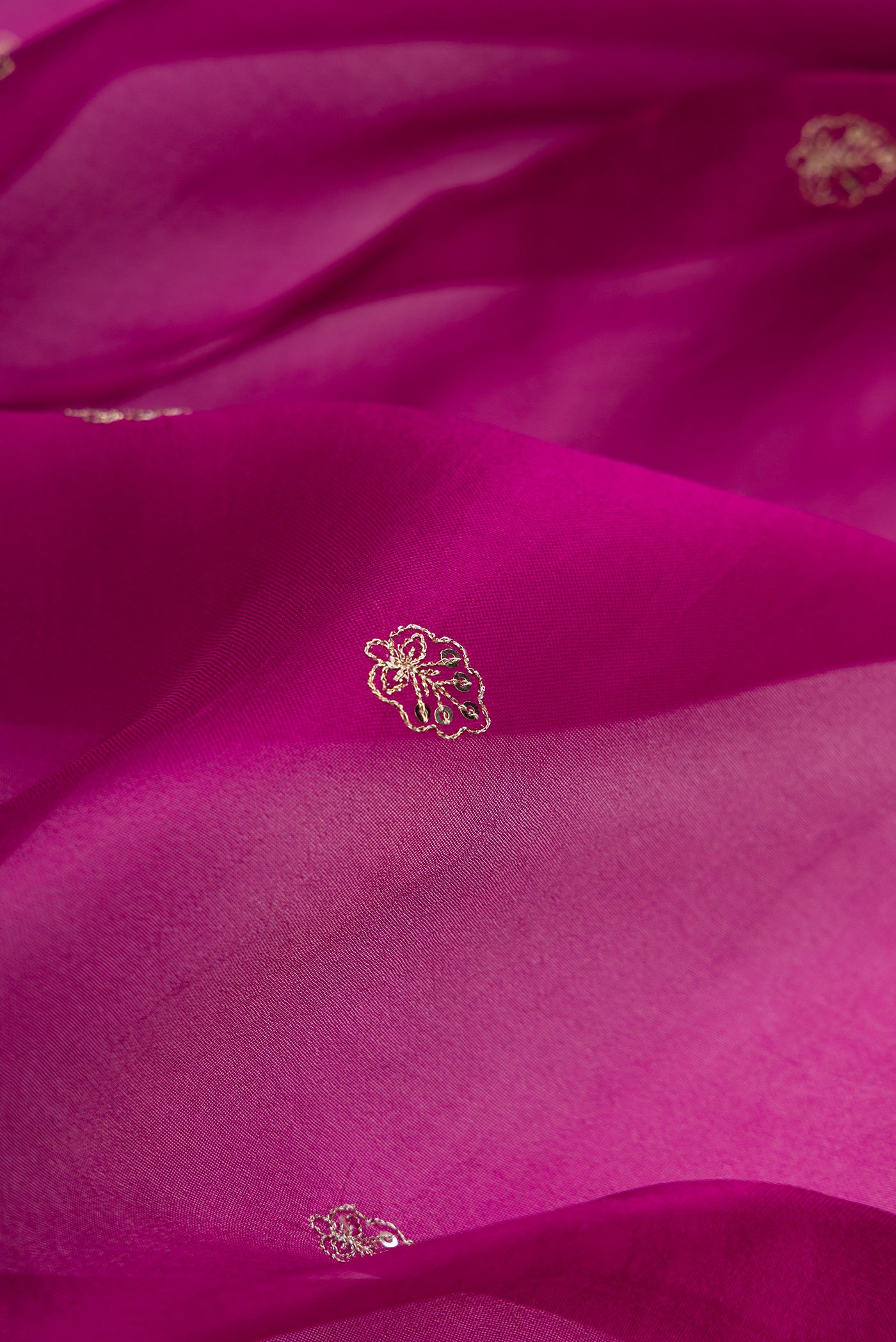Close up of Magenta Dual Tone Organza Silk Saree with Embroidery on the body and Embroidery Border.  displaying folds