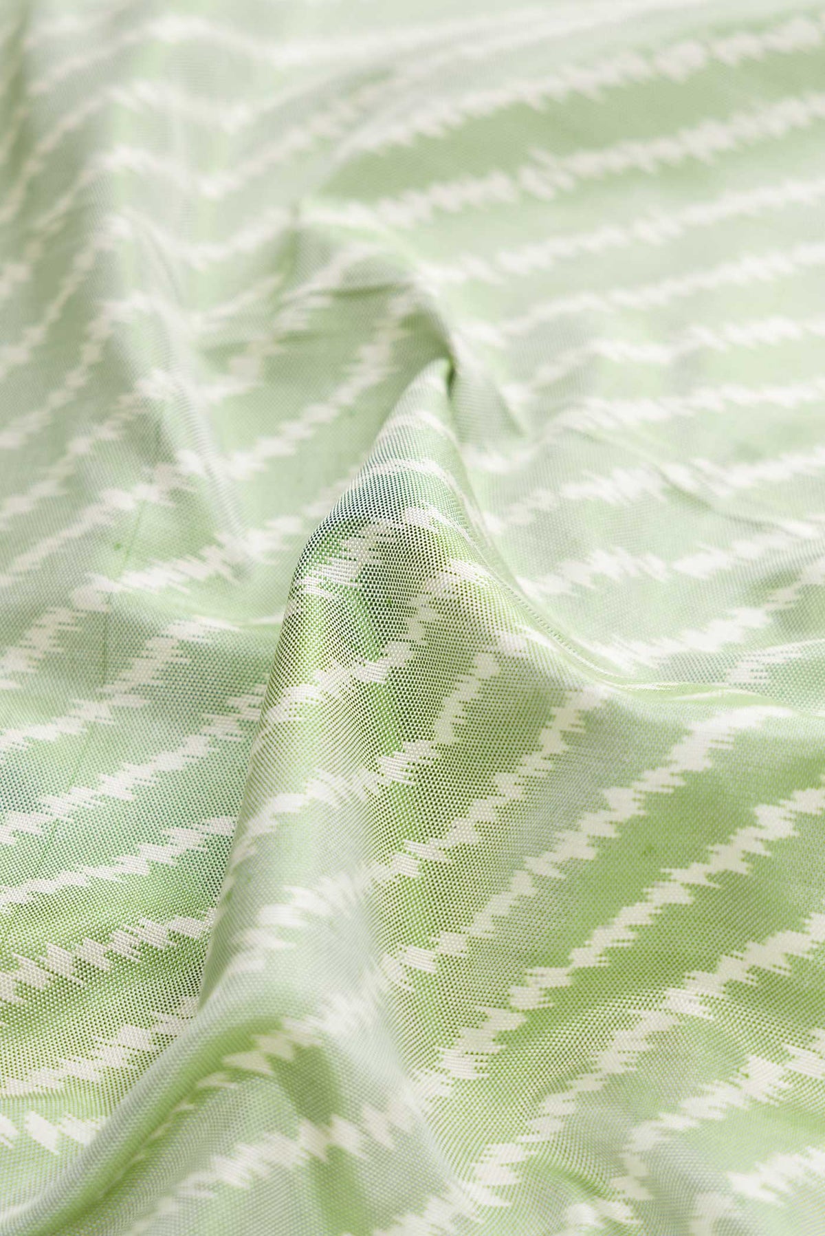 Close up of Green Dual Tone Double Ikat Saree with Ikat Print on the body and Ikat Border displaying folds