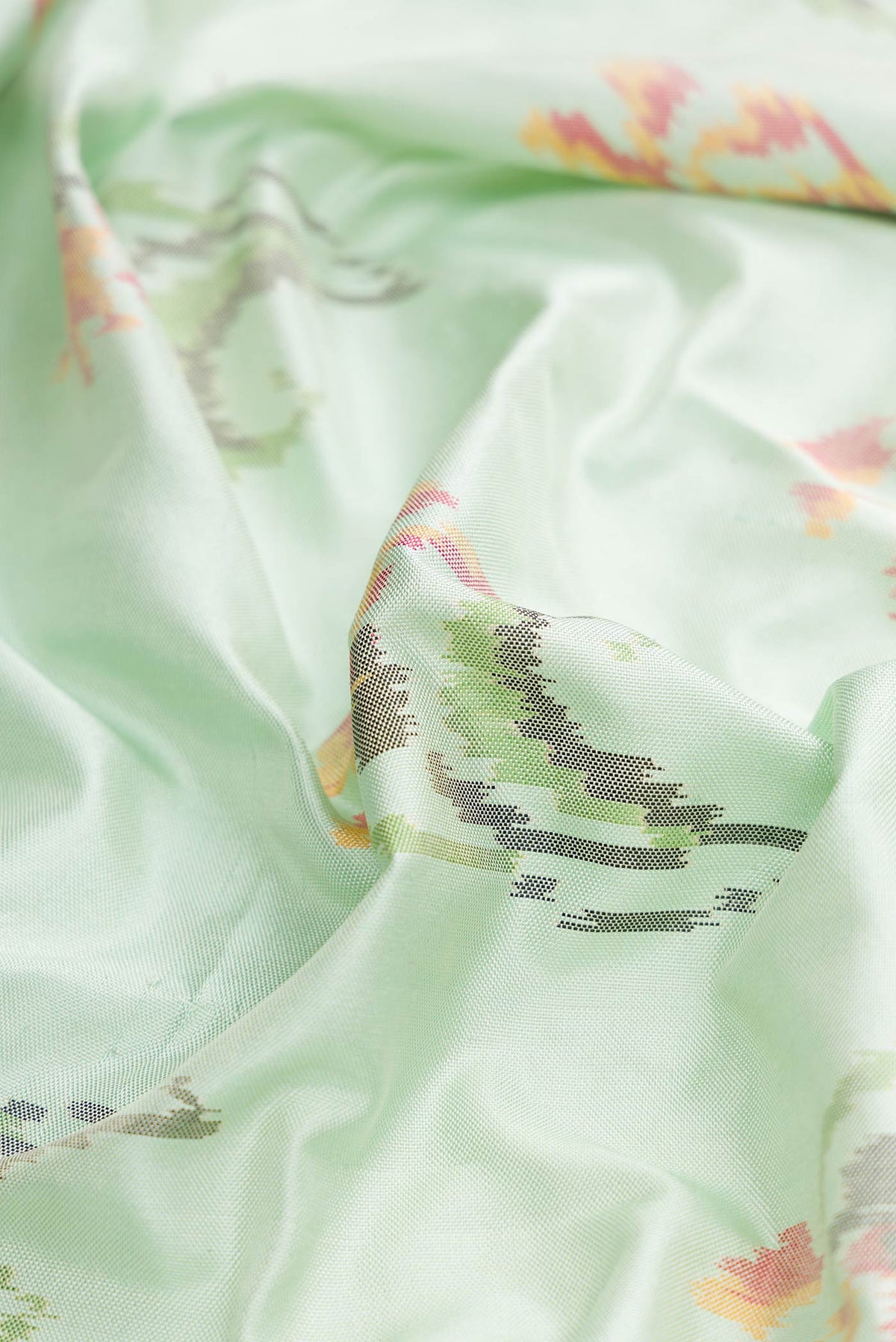 Close up of Light Green Dual Tone Double Ikat Saree with Ikat Print on the body and Zari And Thread Border displaying folds