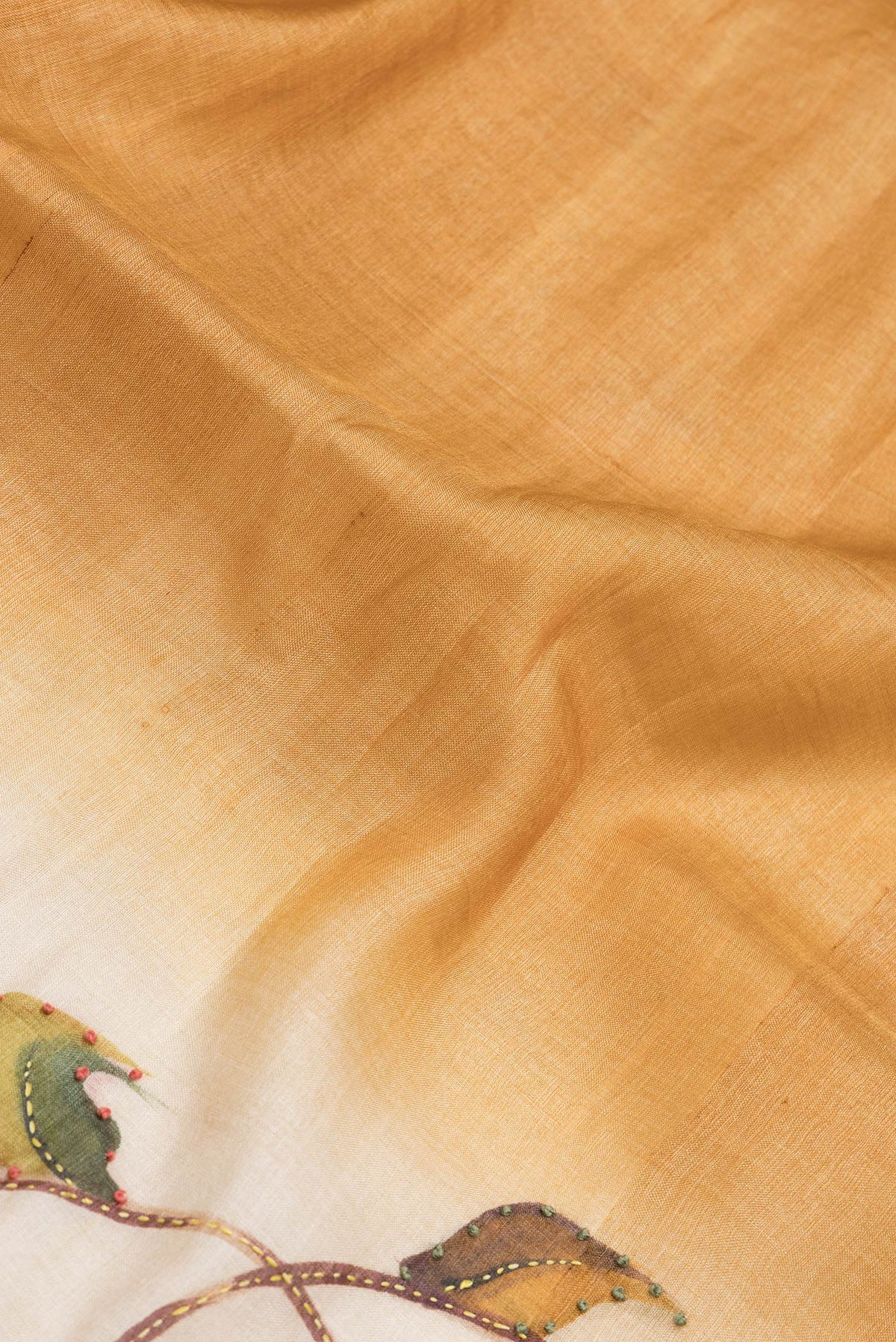 Close up of Mustard Dual Tone Tussar Silk Saree with Embroidery on the body and Zari Border.  displaying folds