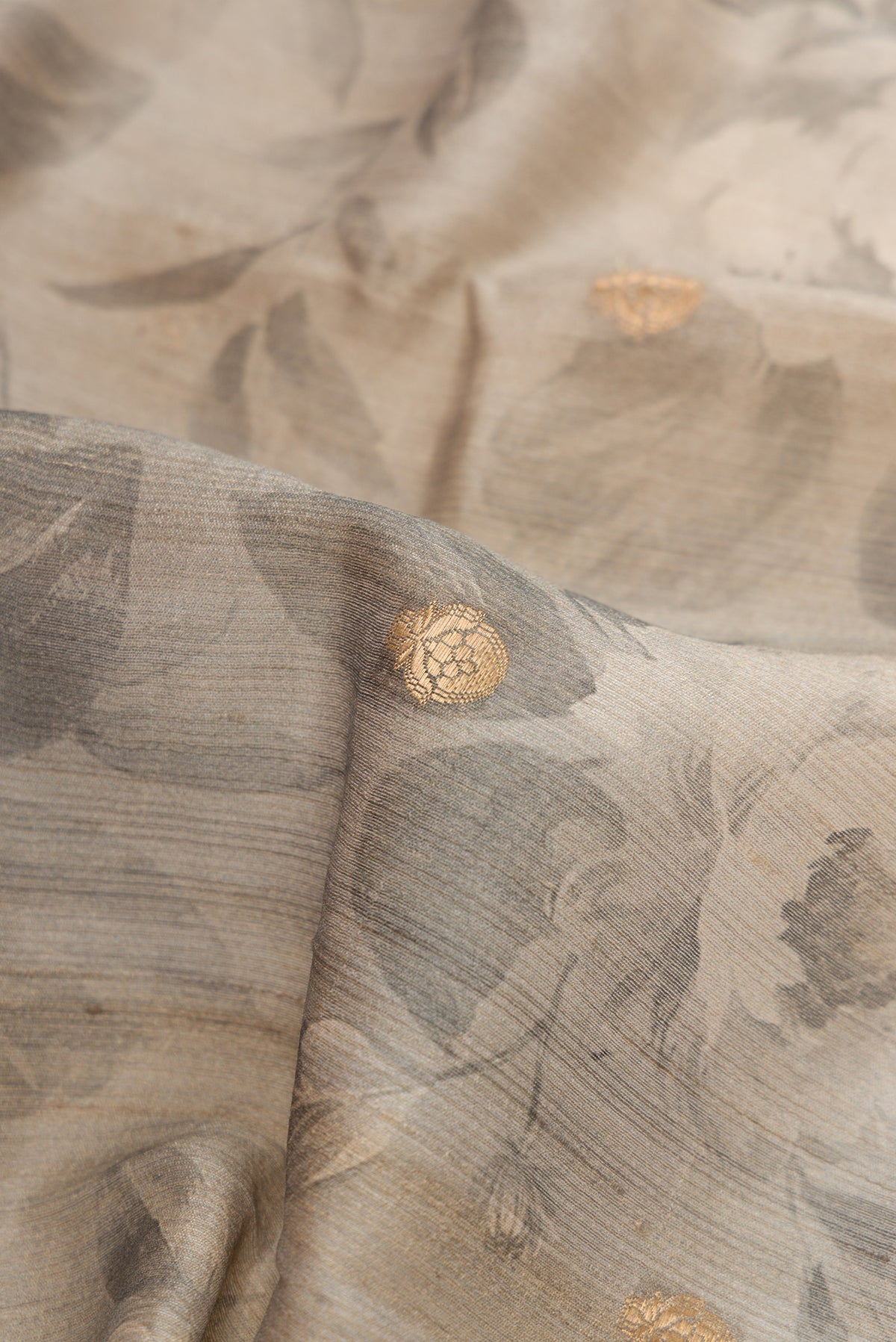 Close up of Grey Dual Tone Tussar Silk Saree with Zari Butta on the body and Zari Border.  displaying folds