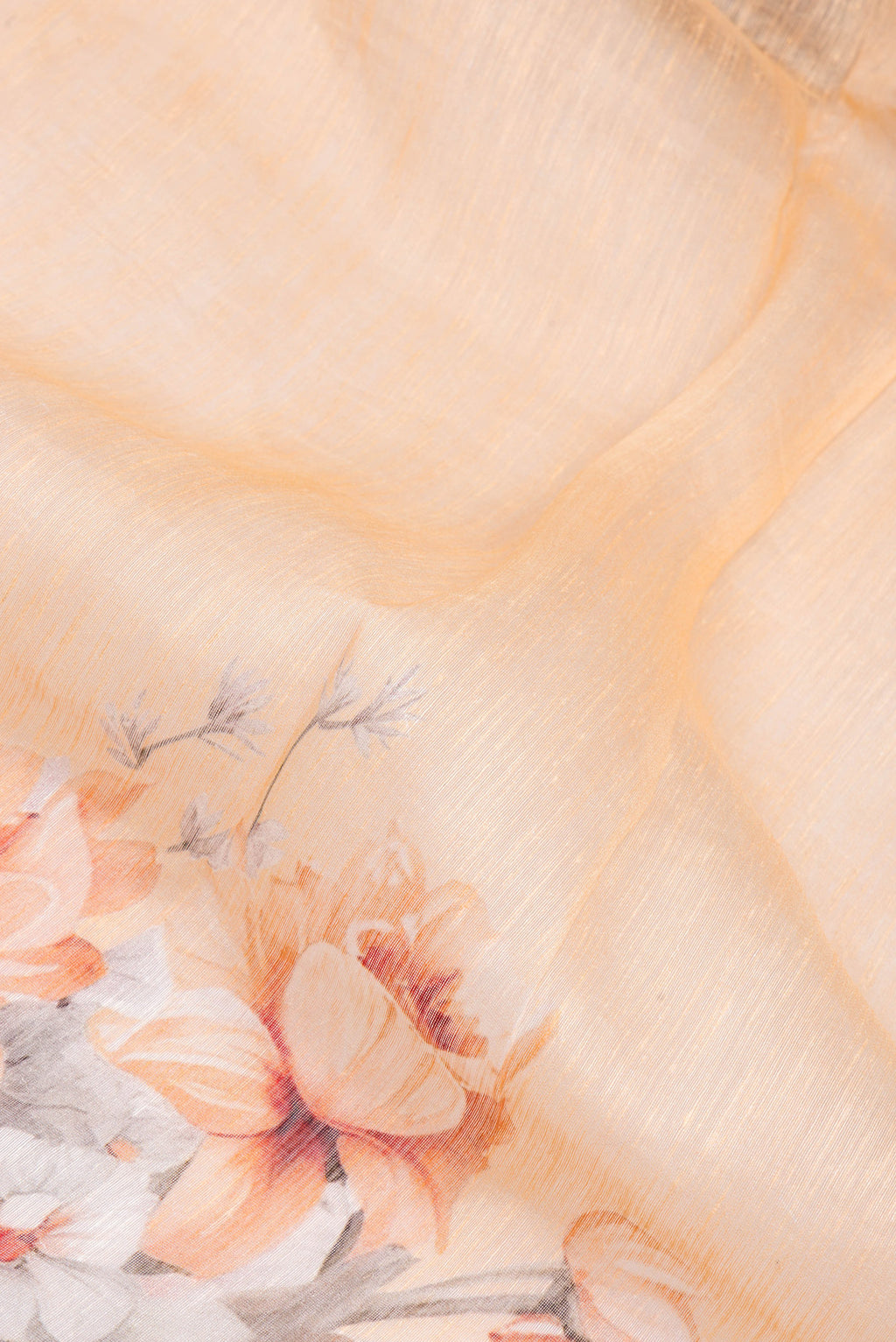 Close up of Golden Peach Linen Saree with Floral Print on the body and Zari Border.  displaying folds