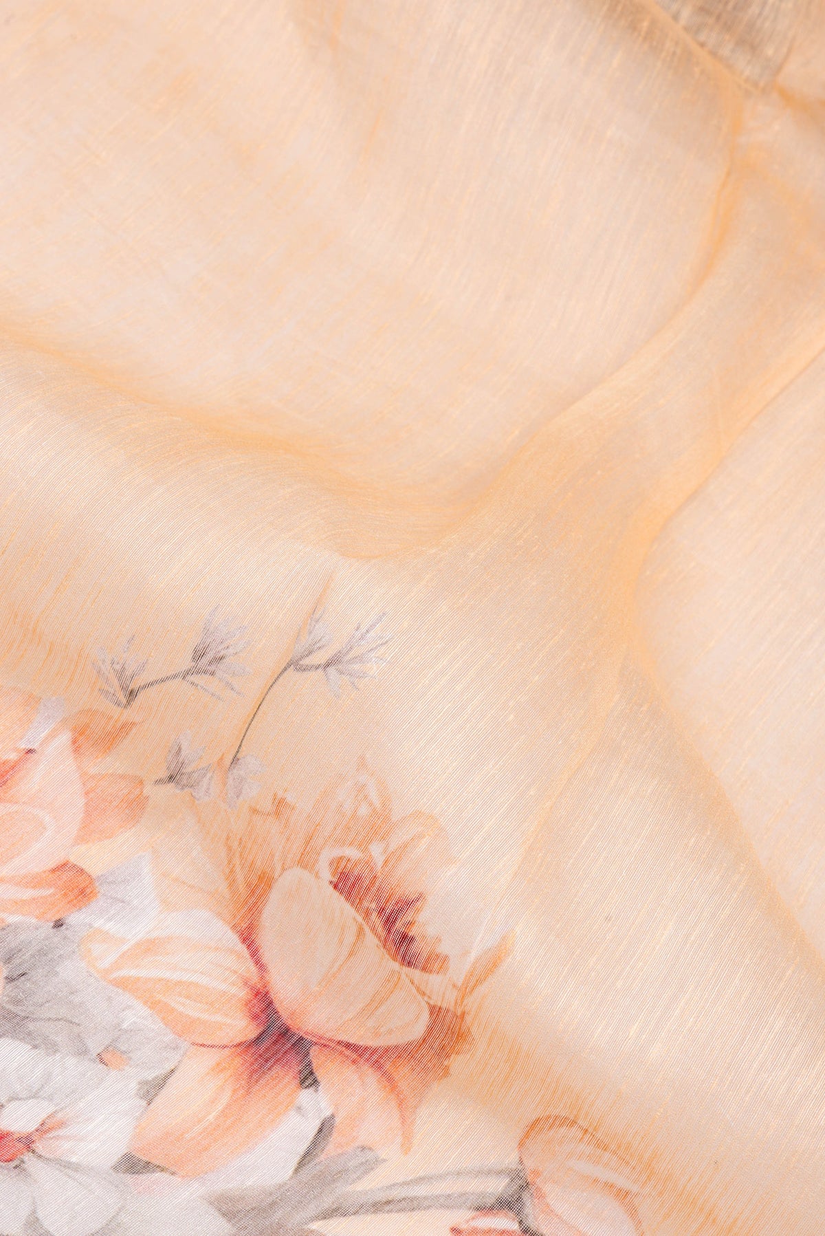 Close up of Golden Peach Linen Saree with Floral Print on the body and Zari Border.  displaying folds