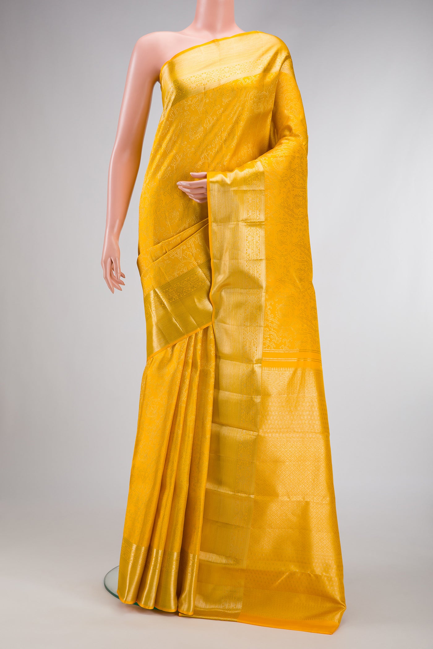 Gold Dual Tone Kanchipuram Silk Saree with Zari Butta on the body and Zari Border.  displayed on a mannequin