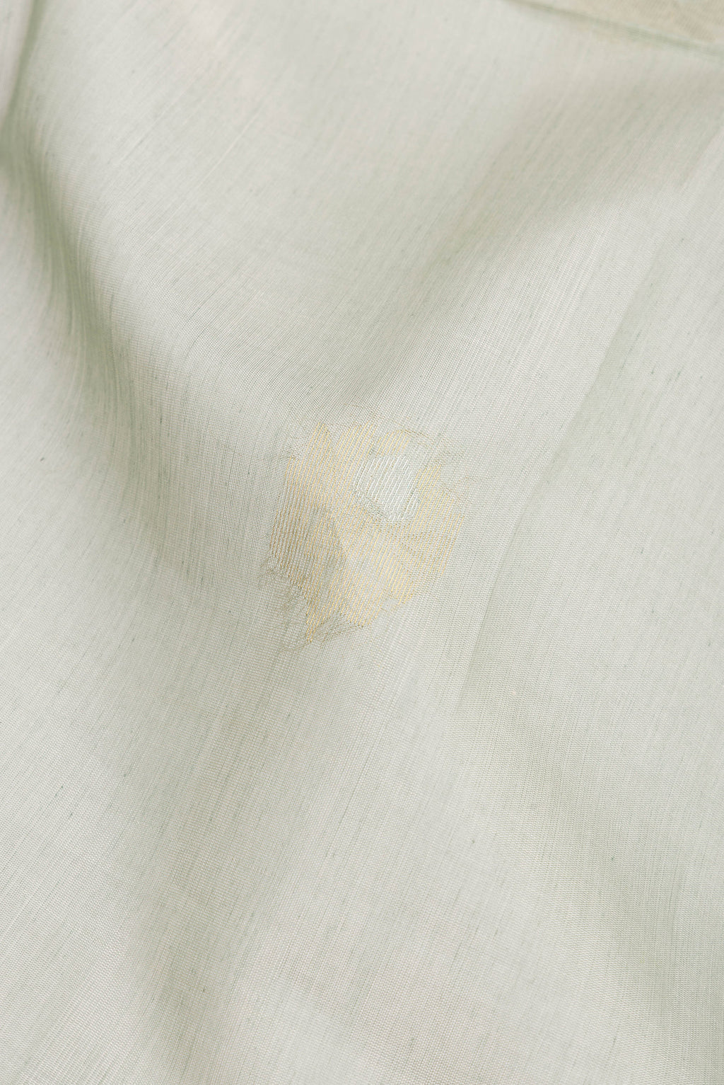 Close up of Light Green Silk Cotton Saree with Zari Butta on the body and Zari Border.  displaying folds