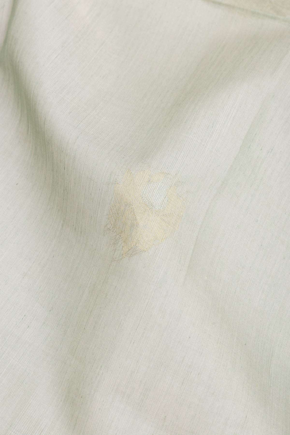 Close up of Light Green Silk Cotton Saree with Zari Butta on the body and Zari Border.  displaying folds
