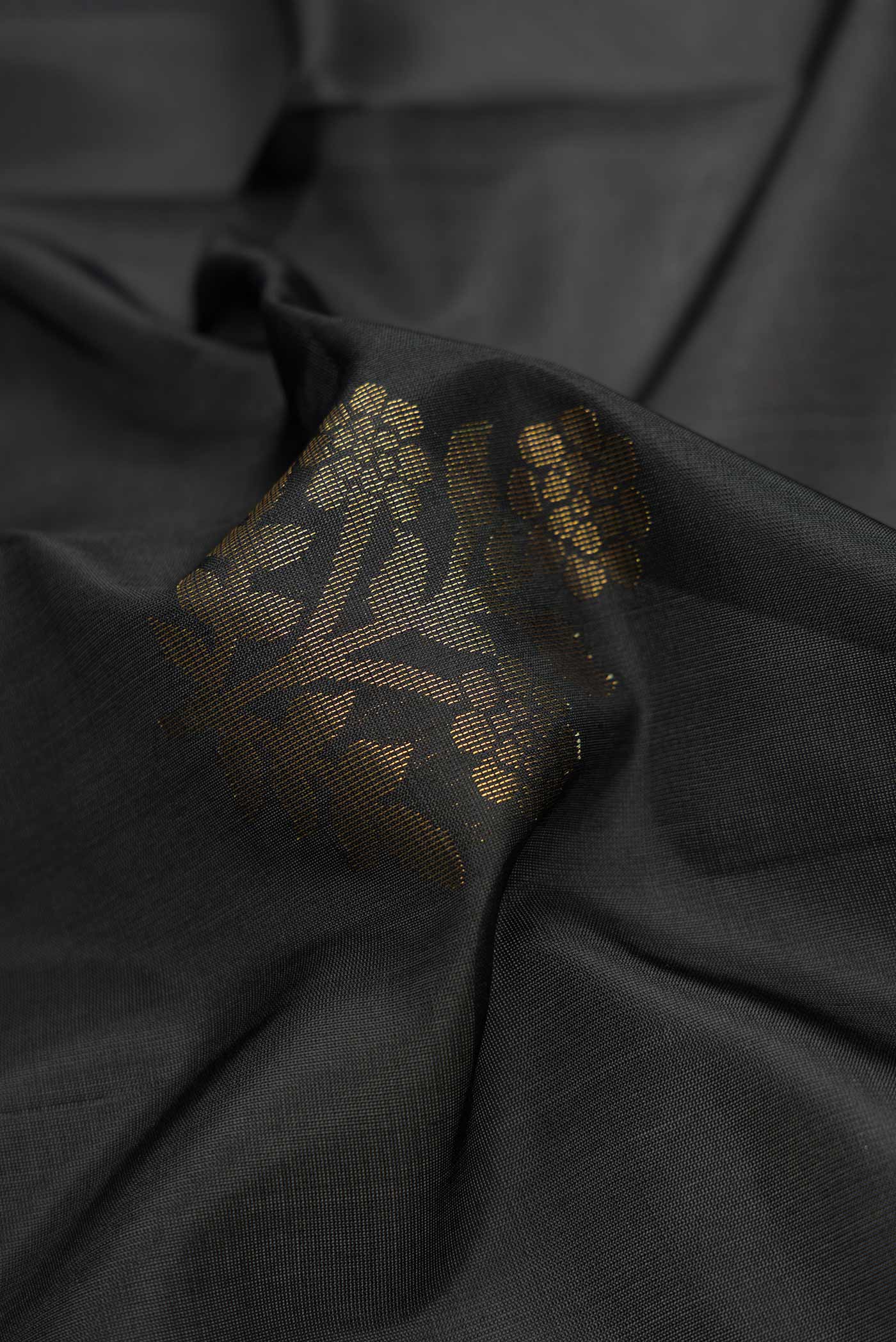Close up of Black Dual Tone Soft Silk Saree with Zari Butta on the body and Zari Border.  displaying folds