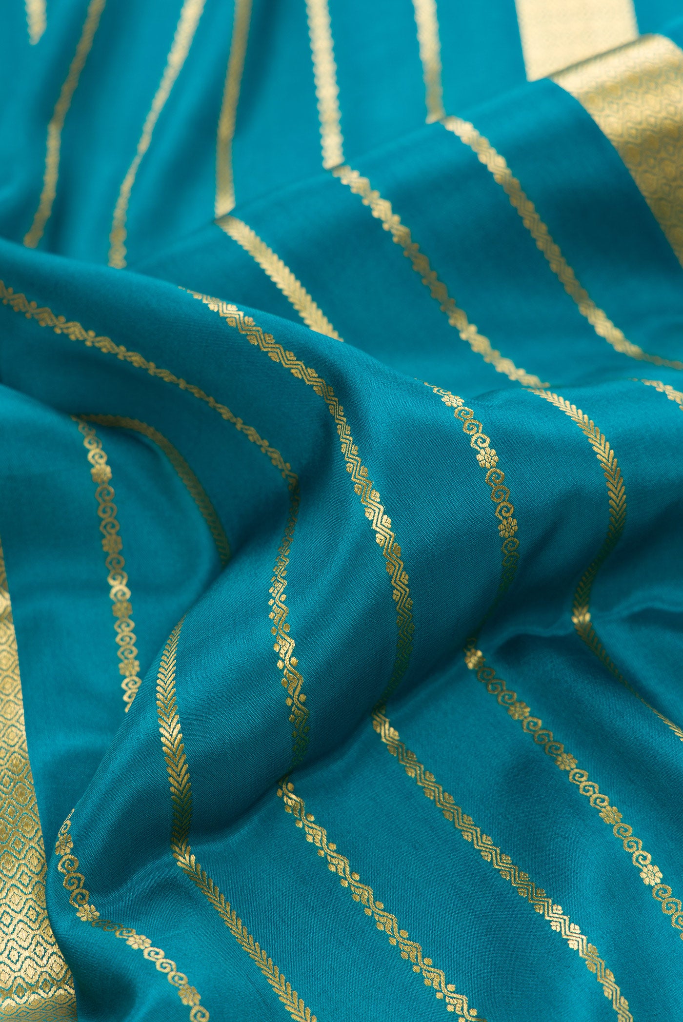Close up of Peacock Blue Dual Tone Mysore Silk Saree with Stripes on the body and Fancy Border.  displaying folds