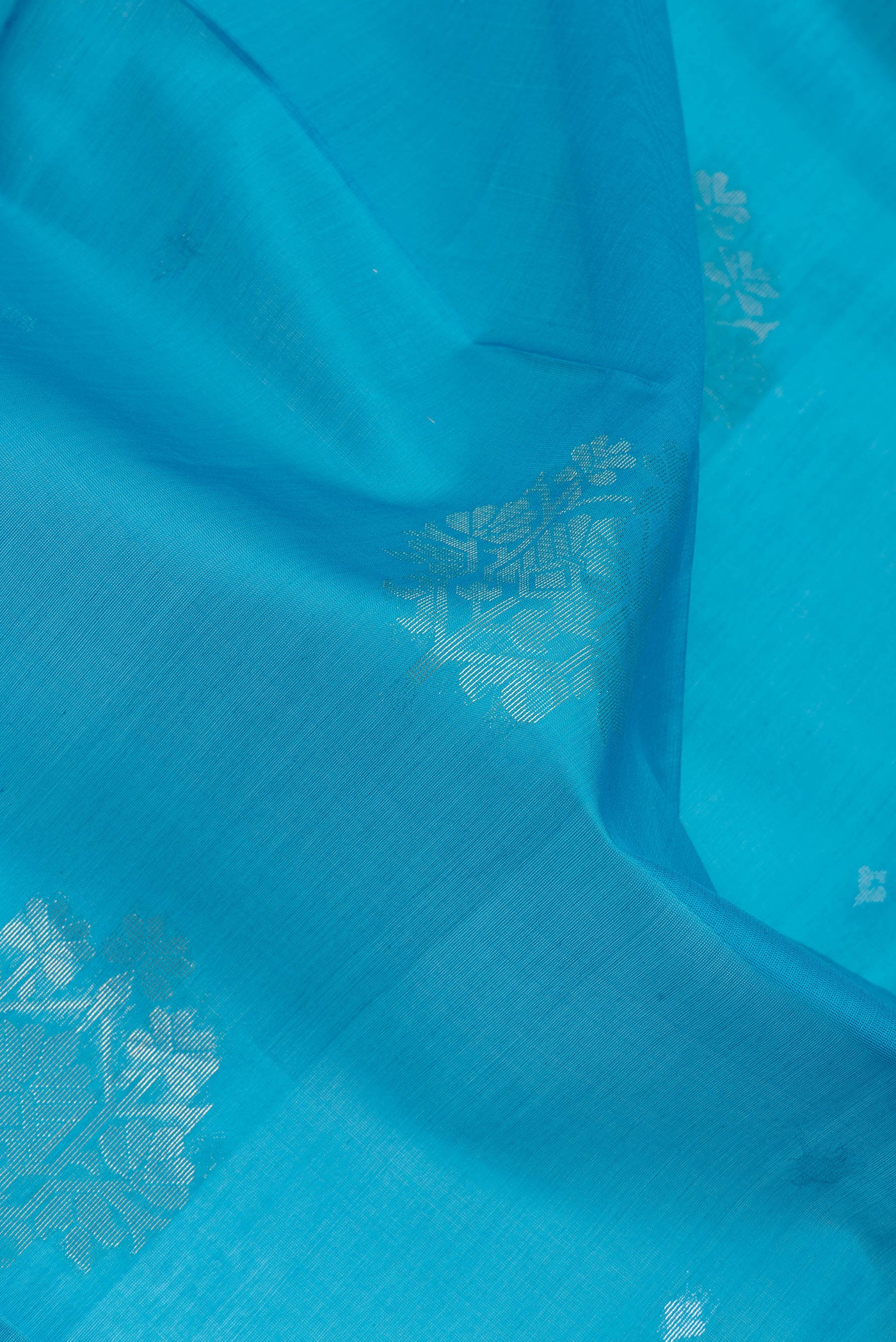 Close up of Sky Blue Silk Cotton Saree with Zari Butta on the body and Zari Border.  displaying folds