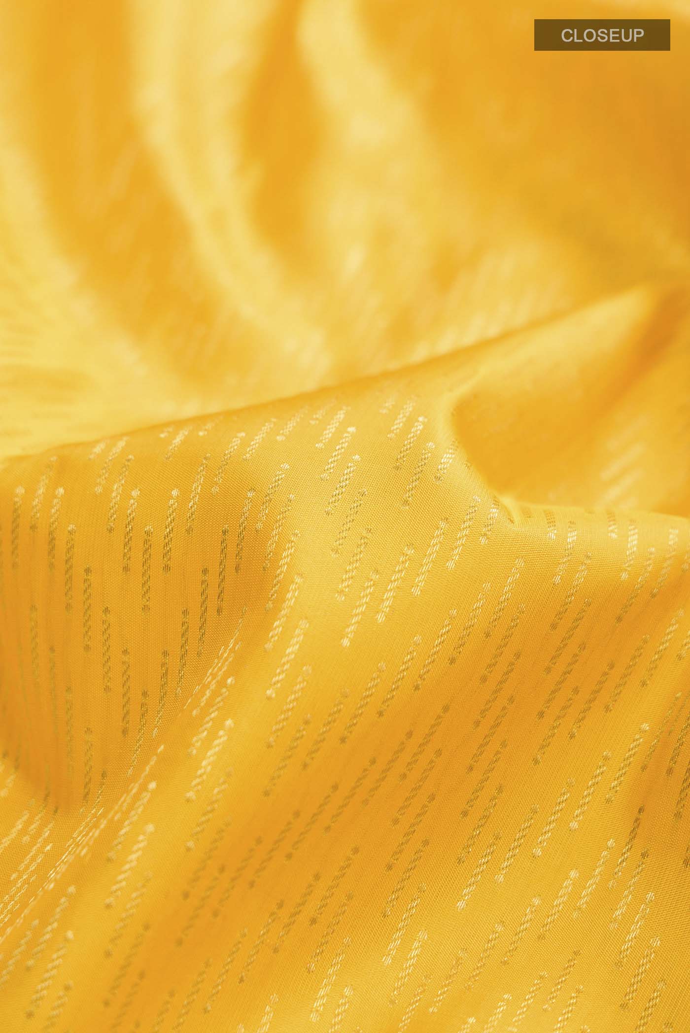 Close up of Yellow Kanchipuram Silk Saree with Stripes on the body and Zari Border displaying folds
