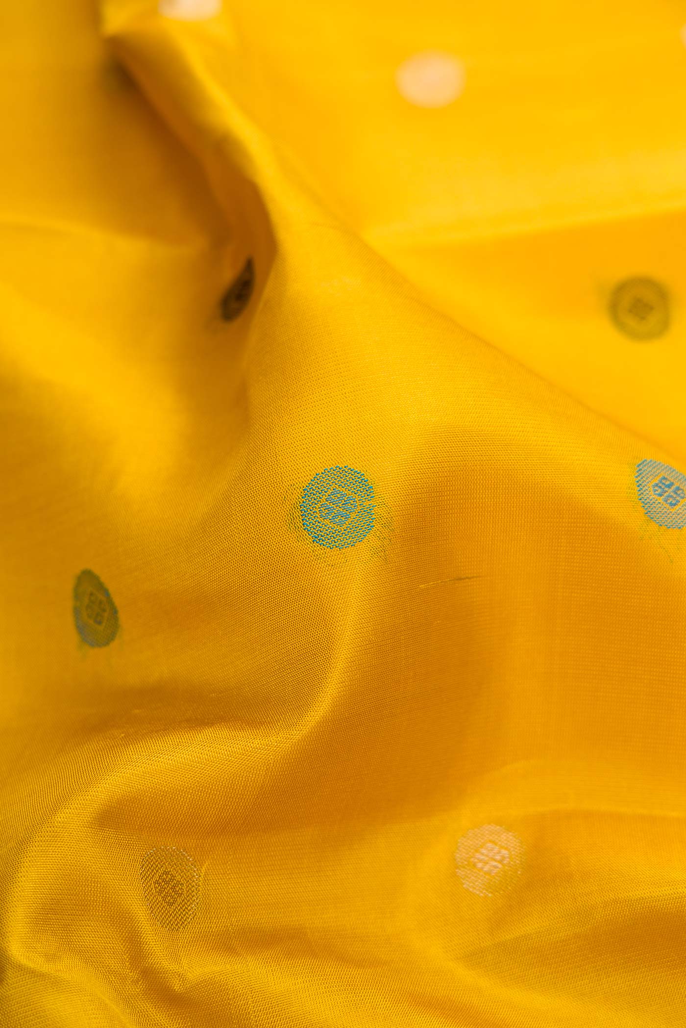 Close up of Mustard Dual Tone Kanchipuram Silk Saree with Zari And Thread Butta on the body and Zari Border.  displaying folds