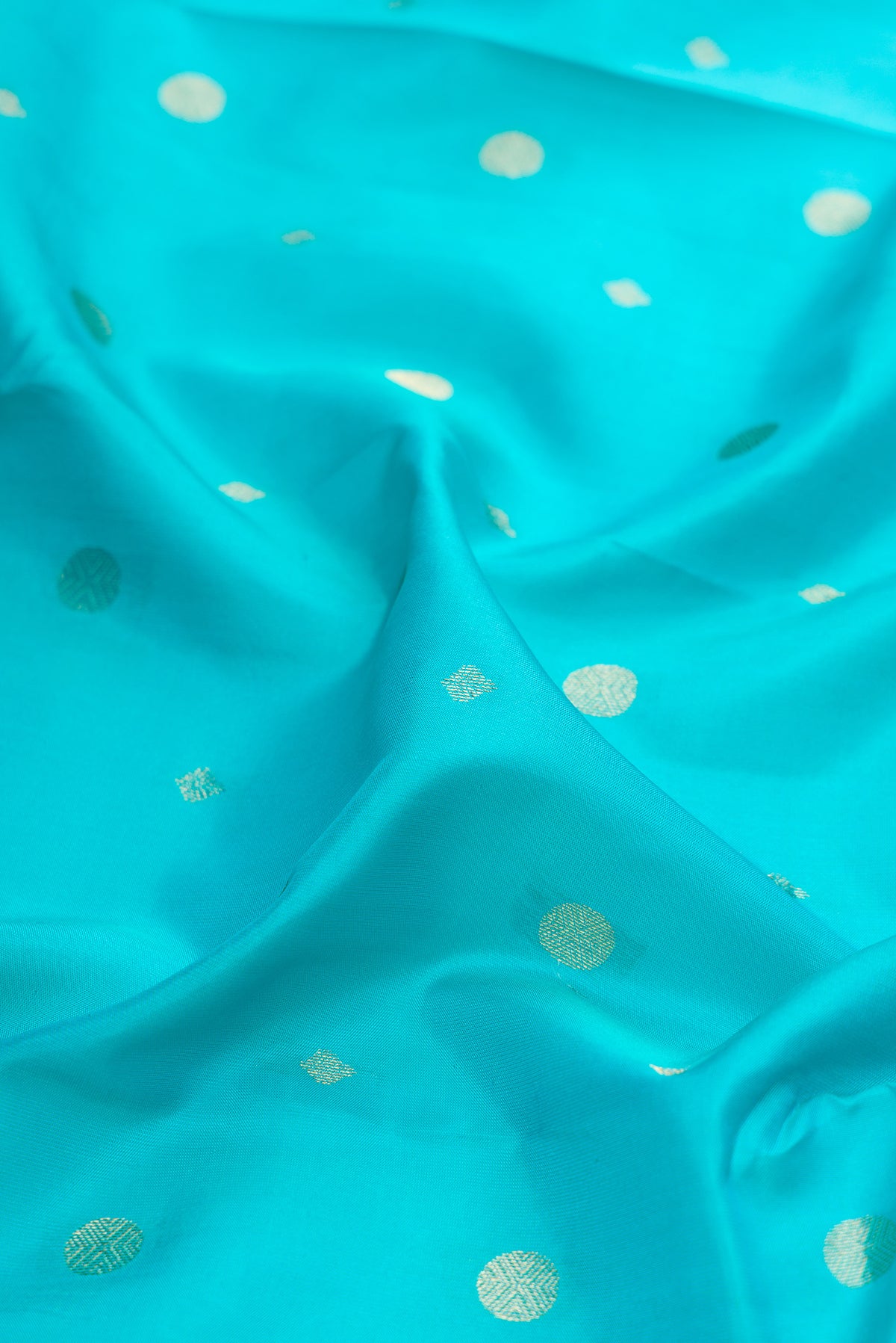 Close up of Turquoise Kanchipuram Silk Saree with Zari Butta on the body and Zari Border.  displaying folds