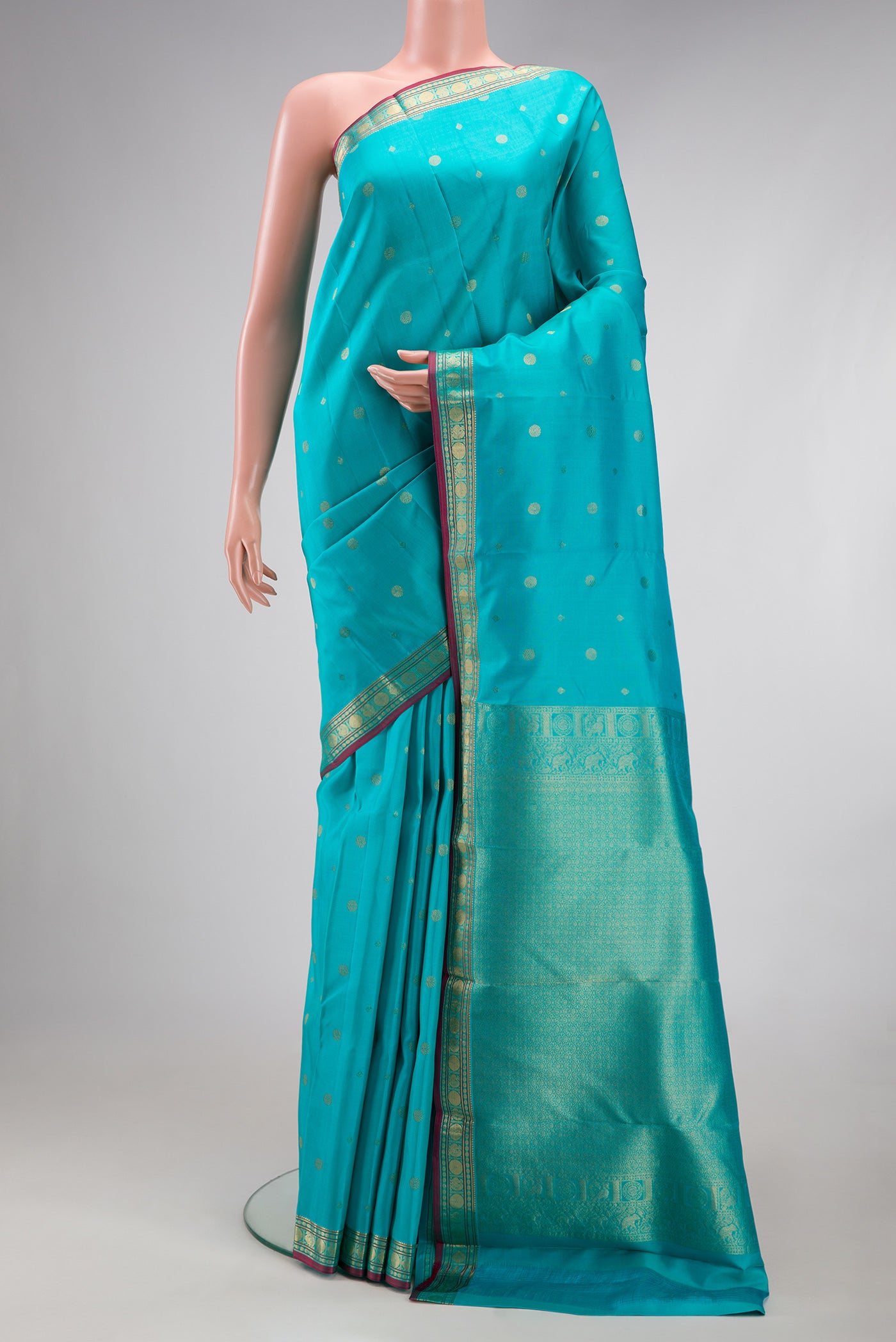 Turquoise Kanchipuram Silk Saree with Zari Butta on the body and Zari Border.  displayed on a mannequin