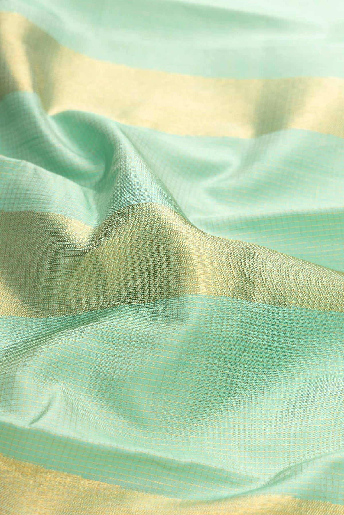 Close up of Pure Silk Pure Zari Pista Green Dual Tone Kanchipuram Saree with Checked design on the body and Fancy Border displaying folds