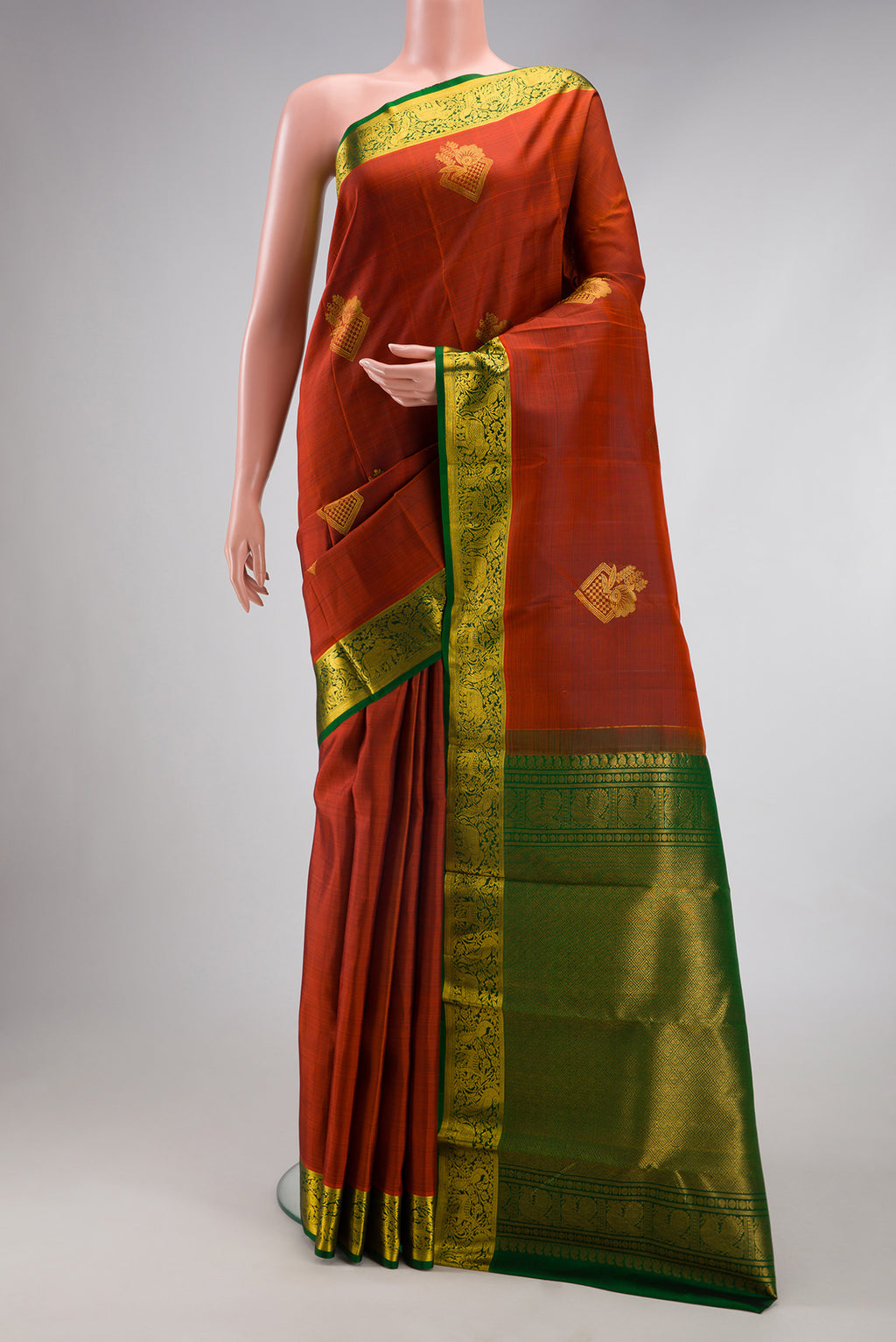 Brick Orange Kanjivaram Silk Saree with Zari Butta on the body and Zari Border.  displayed on a mannequin
