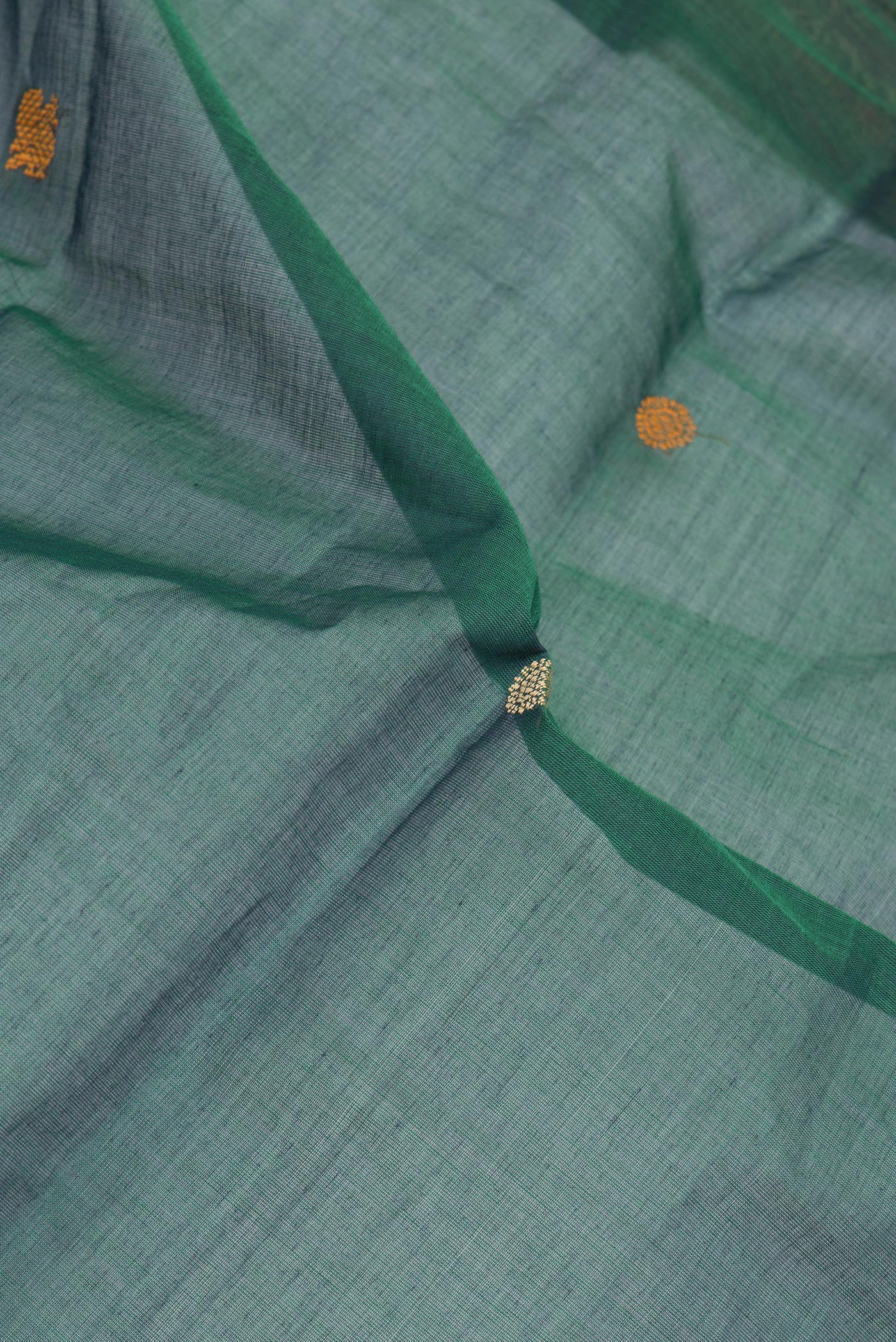 Close up of Bottle Green Dual Tone Kanchi Cotton Saree with Thread Butta on the body and Thread Border.  displaying folds
