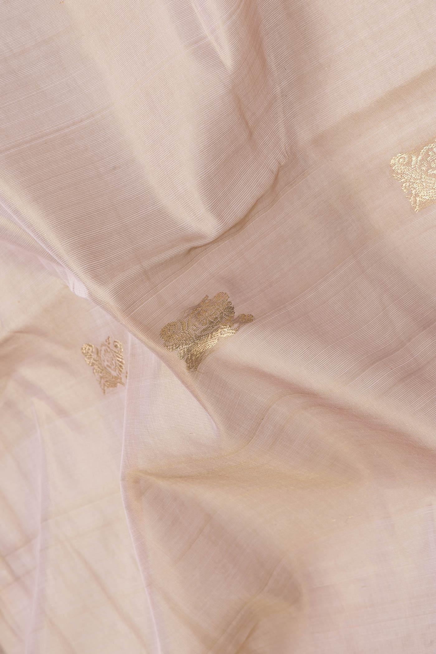 Close up of Rose Gold Dual Tone Silk Cotton Saree with Zari Butta on the body and Zari And Thread Border.  displaying folds