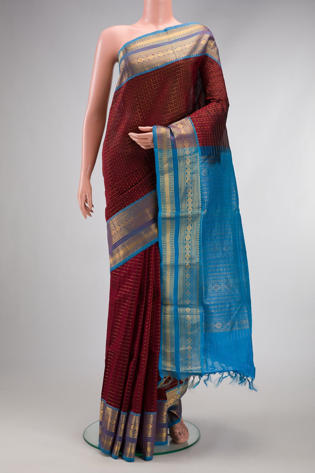 Maroon Silk Cotton Saree with Checked design on the body and Zari Border.  displayed on a mannequin