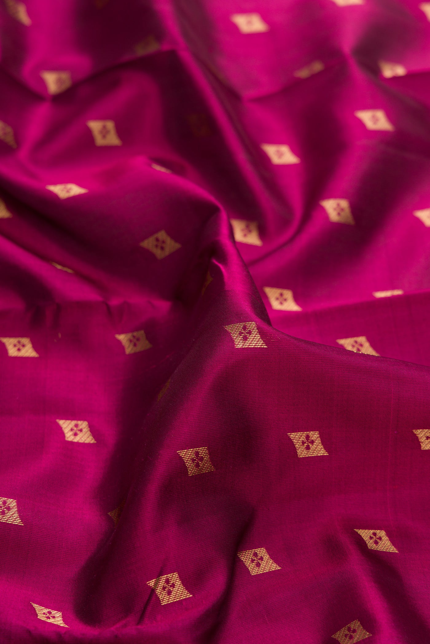 Close up of Magenta Dual Tone Kanchipuram Silk Saree with Zari Butta on the body and Zari Border.  displaying folds