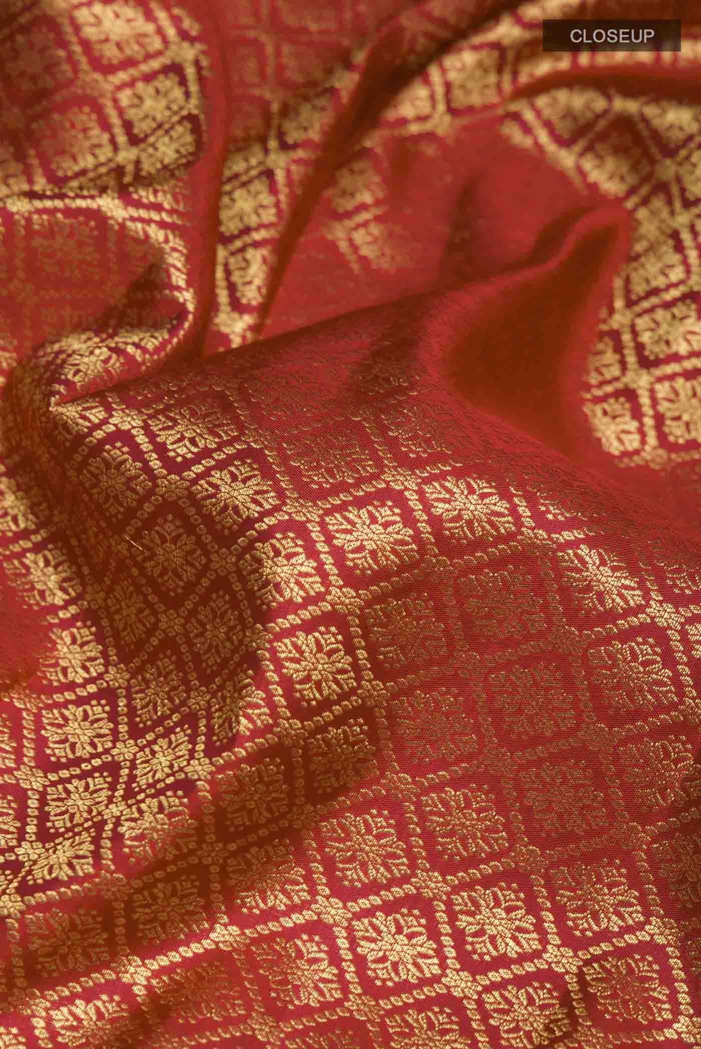 Close up of Maroon Kanchipuram Silk Saree with Zari Butta on the body and Zari Border displaying folds