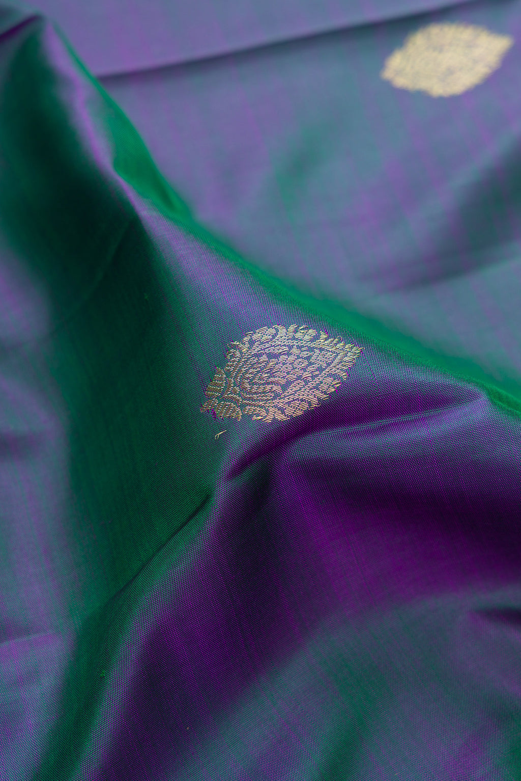 Close up of Peacock Blue Dual Tone Kanchipuram Silk Saree with Zari Butta on the body and Zari Border.  displaying folds