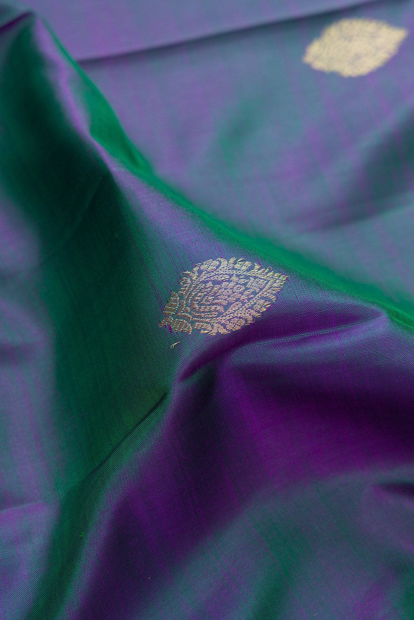 Close up of Peacock Blue Dual Tone Kanchipuram Silk Saree with Zari Butta on the body and Zari Border.  displaying folds