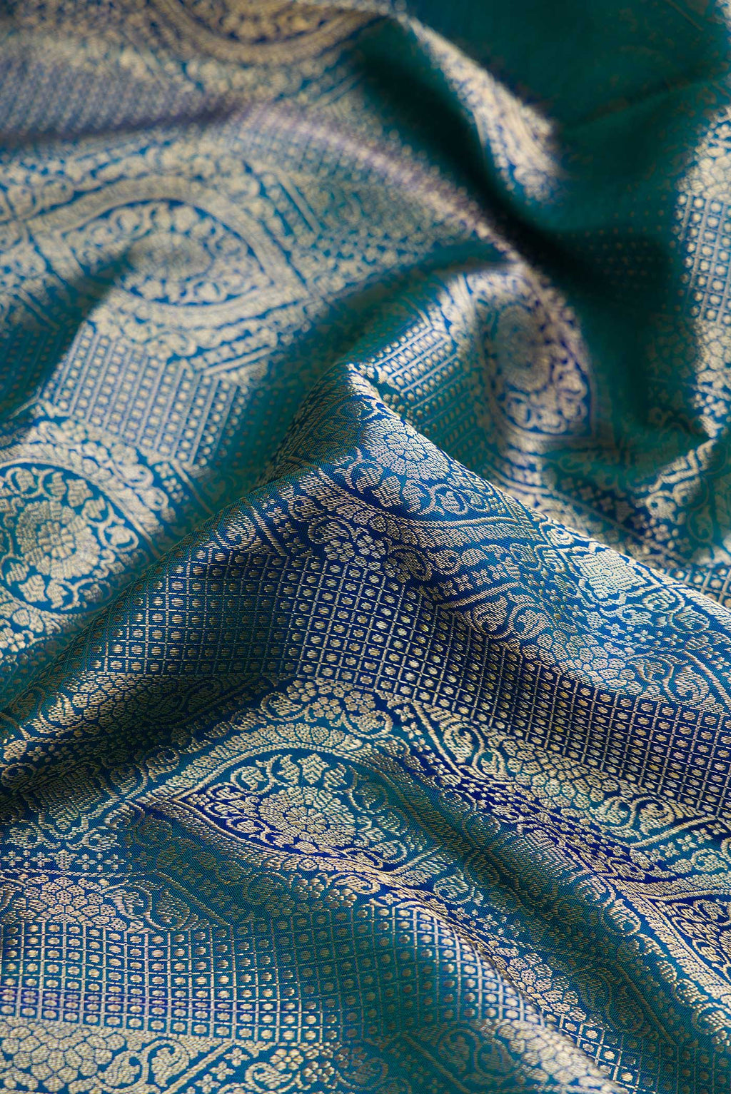 Close up of Peacock Blue Dual Tone Kanchipuram Silk Saree with Zari Brocade on the body and Zari Border.  displaying folds