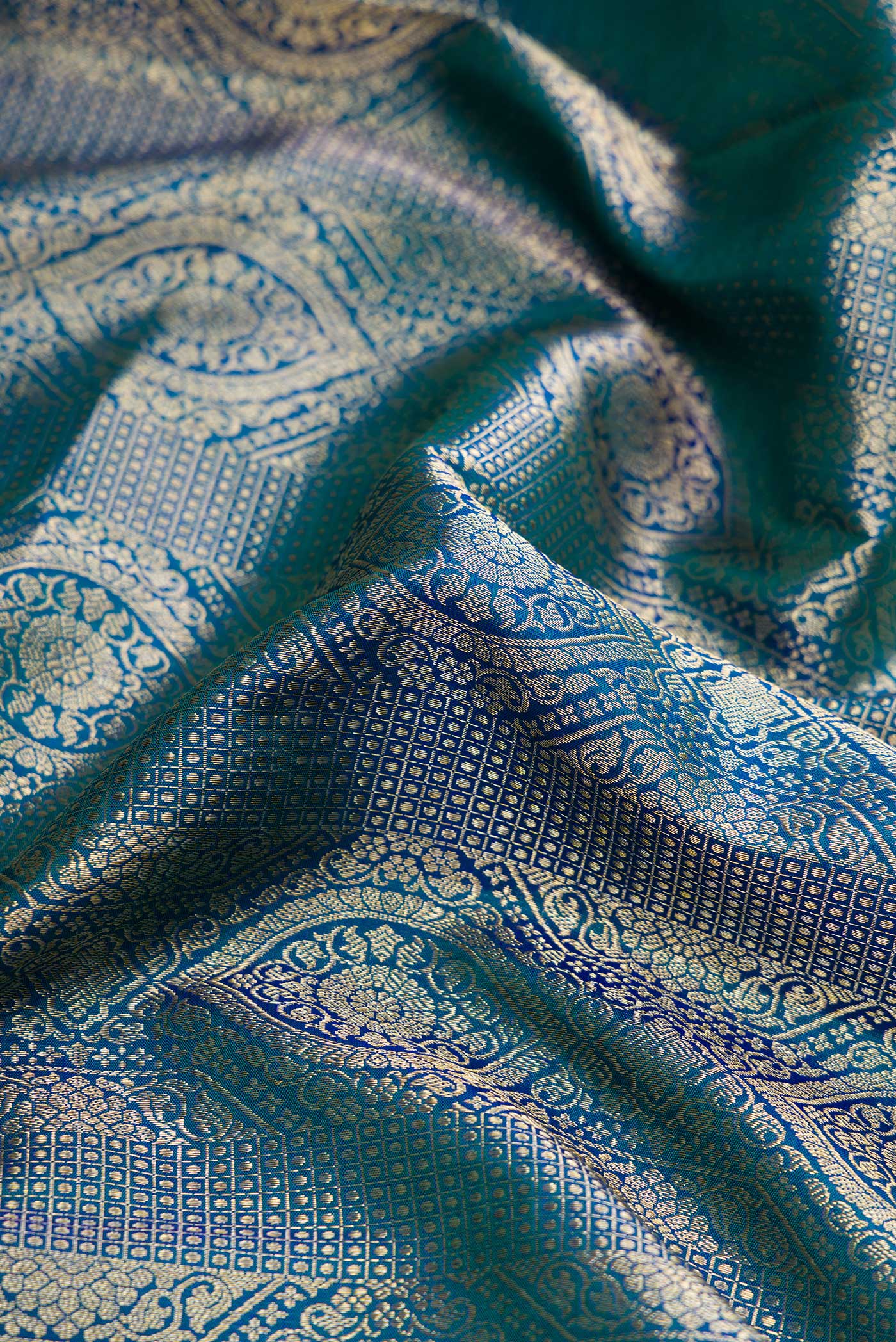 Close up of Peacock Blue Dual Tone Kanchipuram Silk Saree with Zari Brocade on the body and Zari Border.  displaying folds
