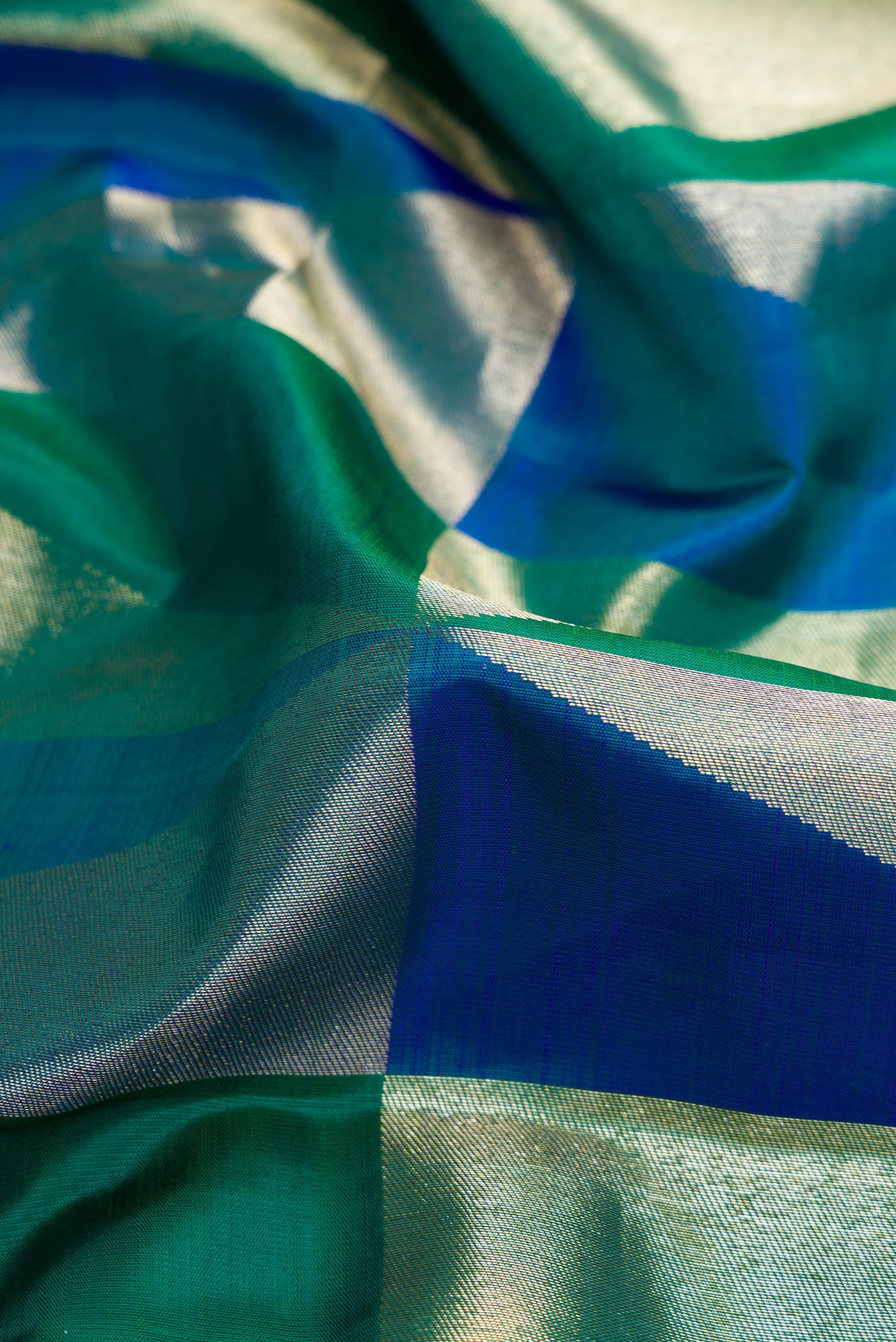 Close up of Green and Peacock Blue Color Kanchipuram Silk Saree with Zari Brocade on the body and Without Border.  displaying folds