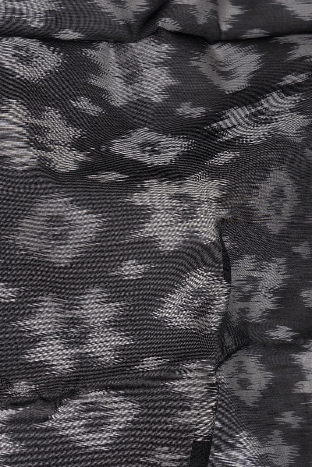 Close up of Black Silk Cotton Saree with Ikat Print on the body and Zari Border.  displaying folds
