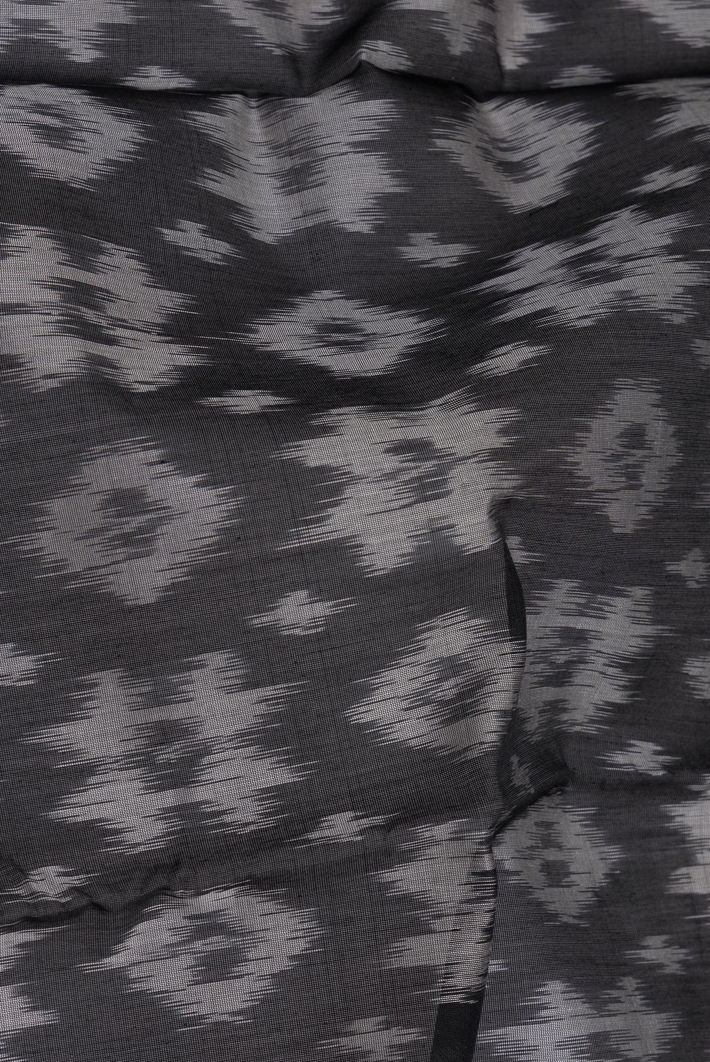 Close up of Black Silk Cotton Saree with Ikat Print on the body and Zari Border.  displaying folds