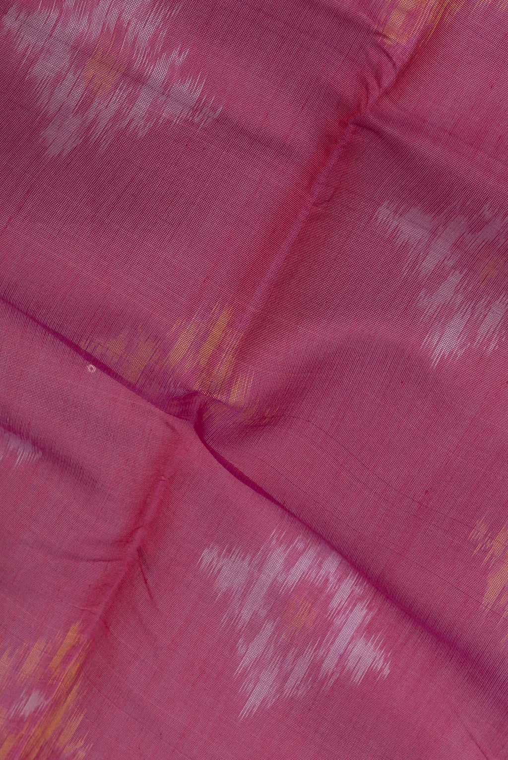 Close up of Dark Pink Silk Cotton Saree with Ikat Print on the body and Zari Border.  displaying folds