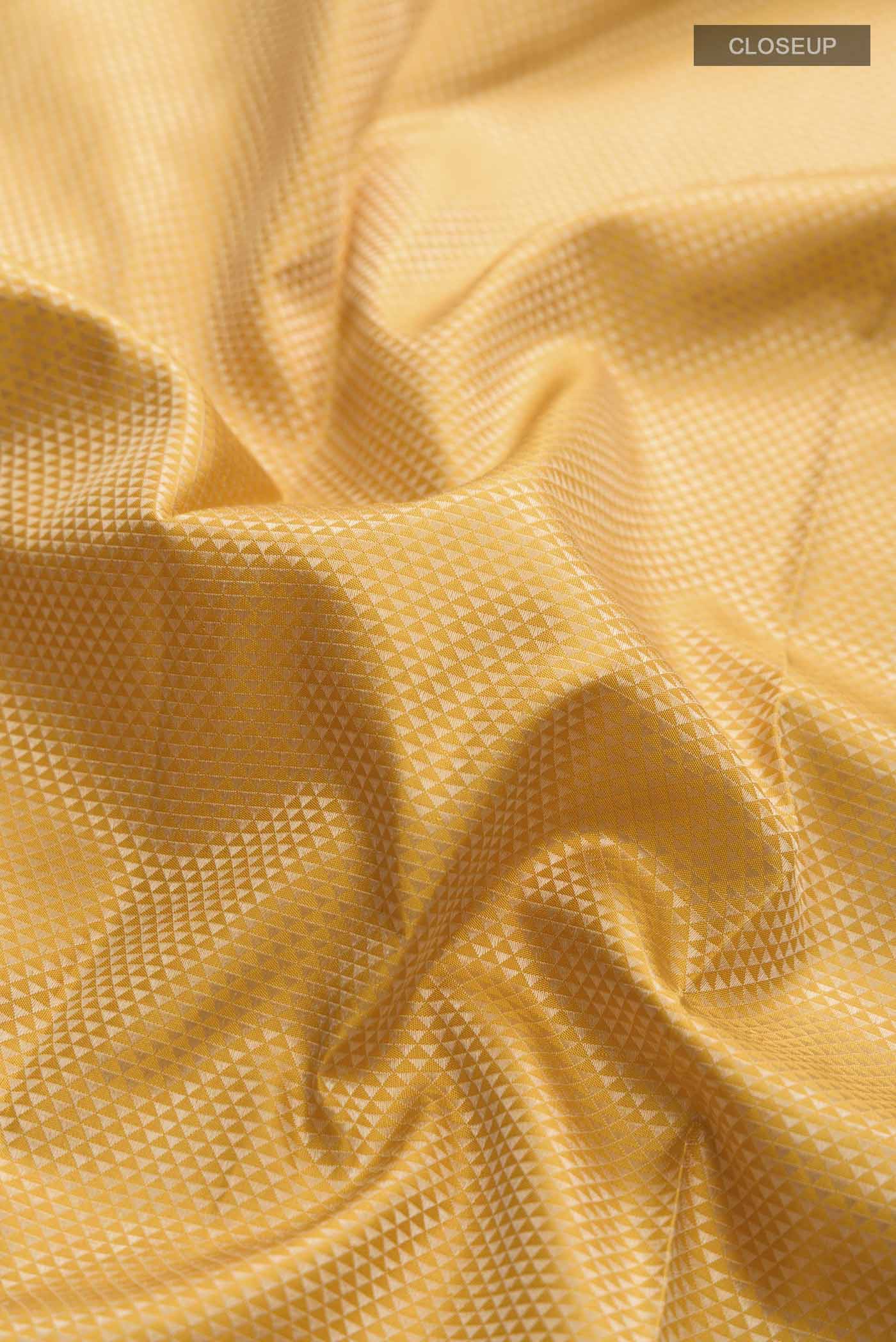 Close up of Yellow Kanchipuram Silk Saree with Jacquard design on the body and Thread Border displaying folds