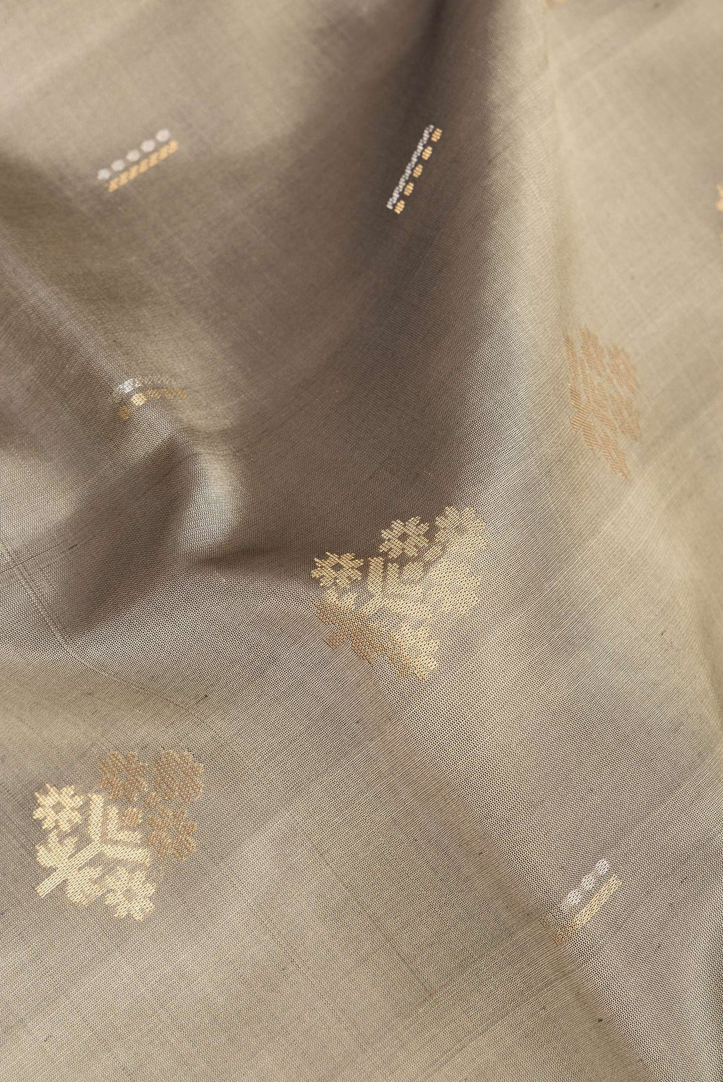 Close up of Pure Silk Grey Soft Saree with Zari Butta on the body and Zari Border.  displaying folds