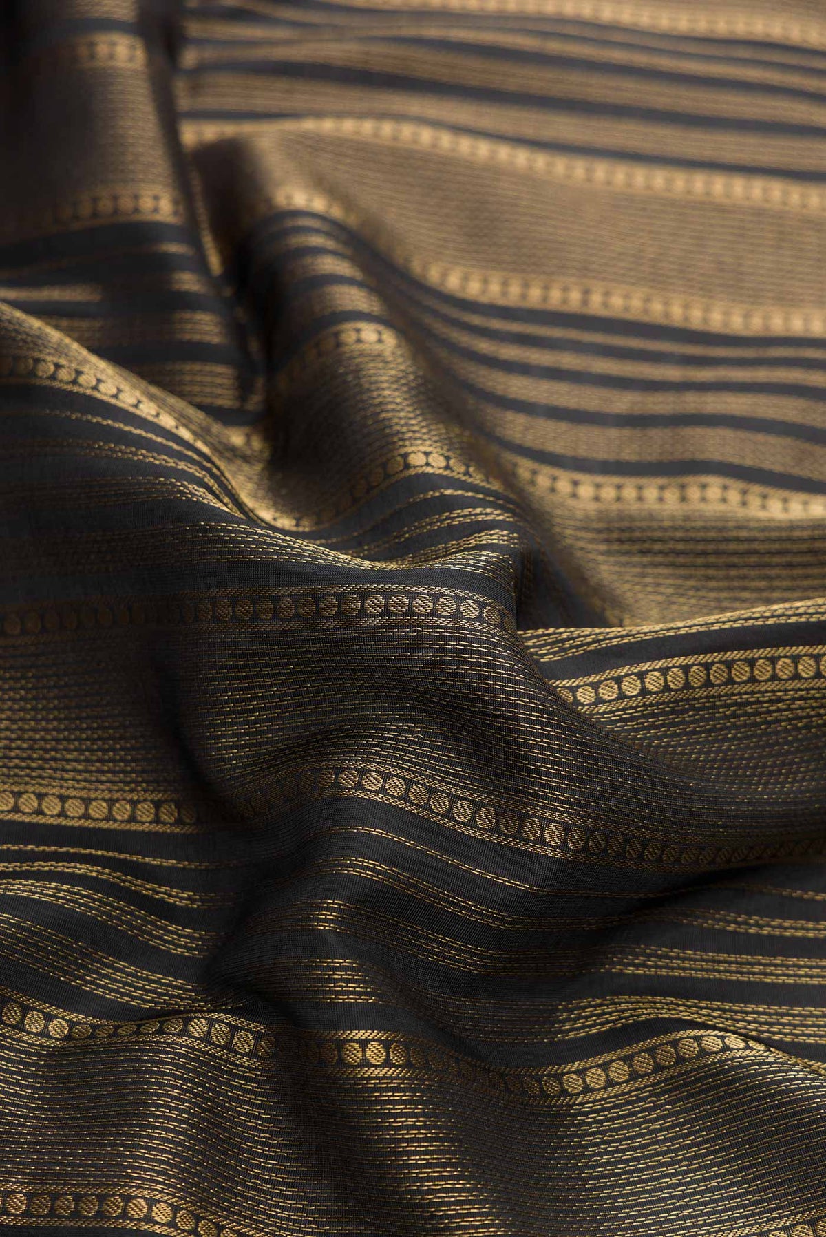 Close up of Black Dual Tone Soft Silk Saree with Stripes on the body and Zari Border displaying folds
