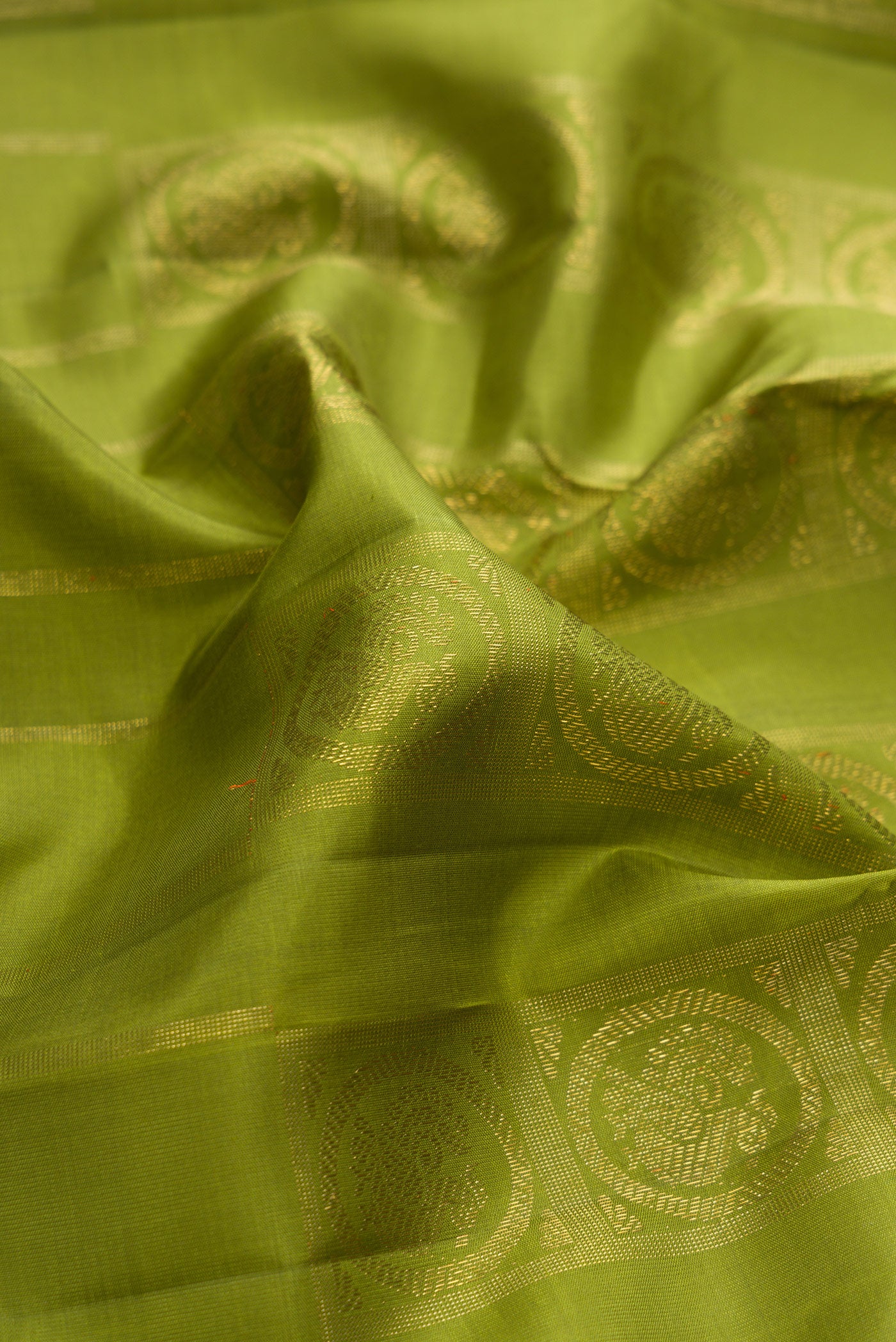 Close up of Pure Silk Pure Zari Green Dual Tone Kanjivaram Saree with Zari Butta on the body and Without Border.  displaying folds