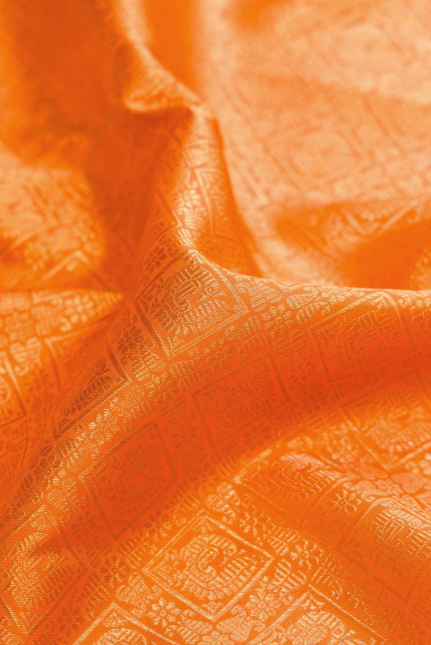 Close up of Pure Silk Pure Zari Orange Dual Tone Kanchipuram Saree with Zari Brocade on the body and Zari Border displaying folds