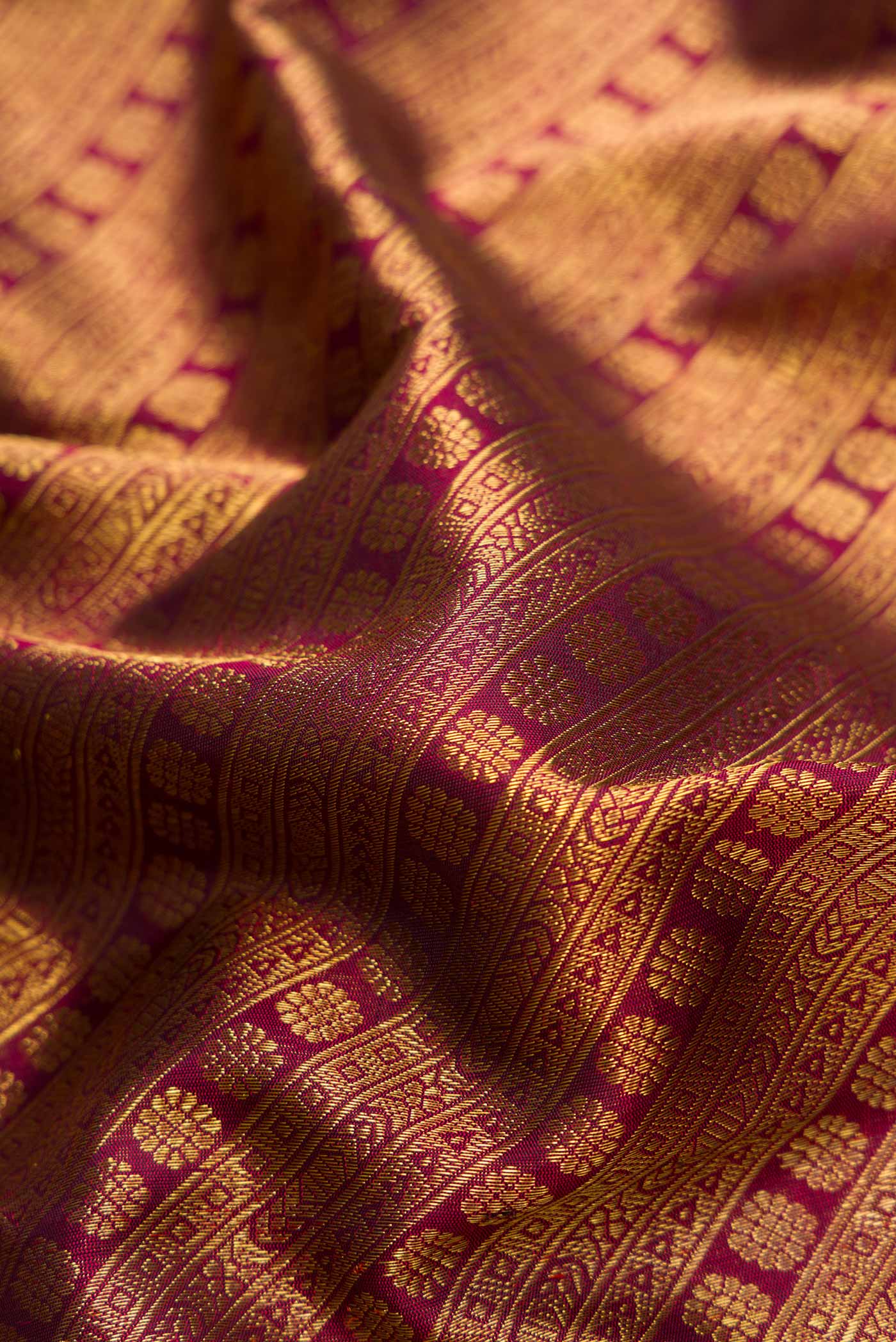 Close up of Pure Silk Pure Zari Maroon Dual Tone Kanjivaram Saree with Zari Brocade on the body and Zari Border.  displaying folds