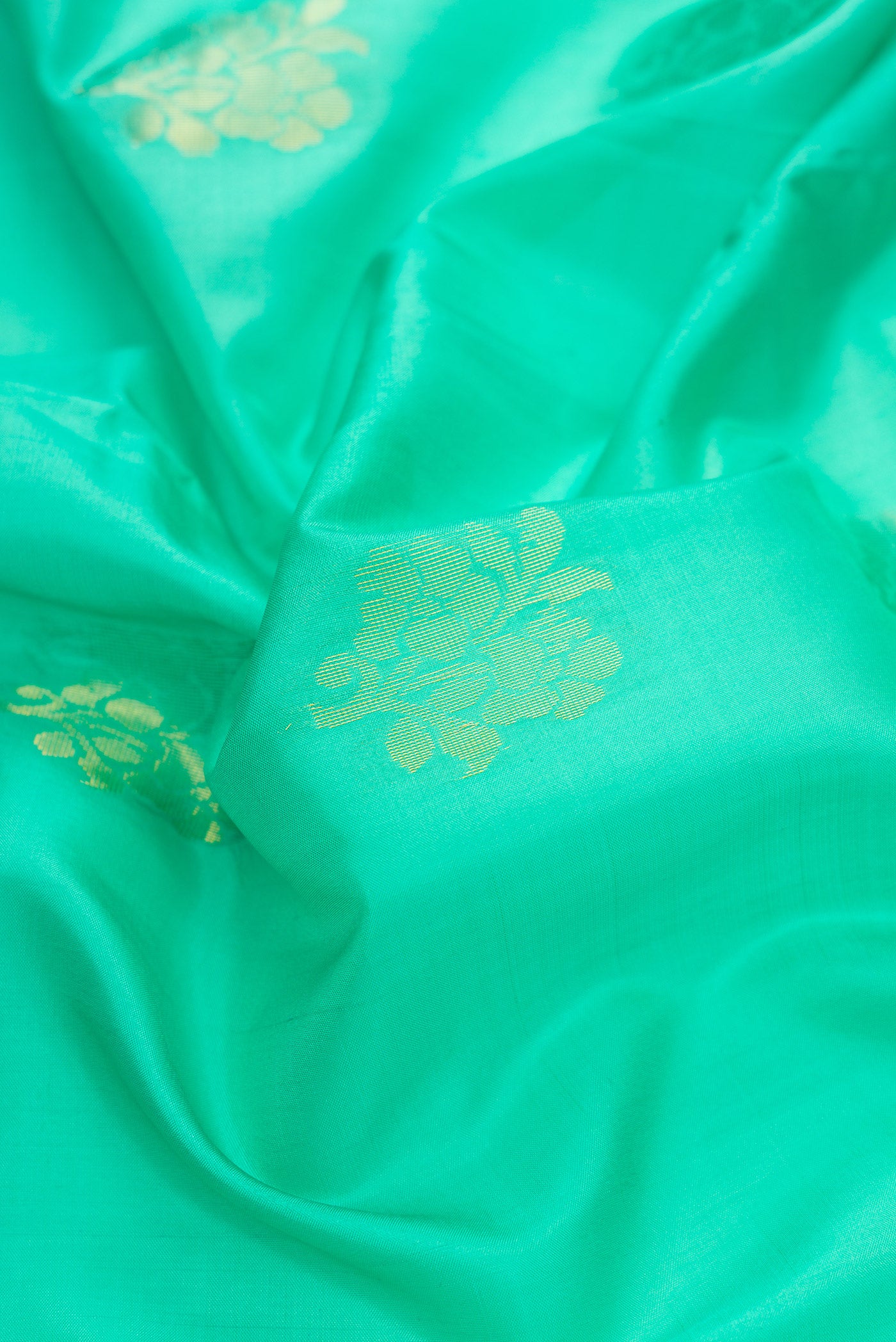 Close up of Sea Green Dual Tone Soft Silk Saree with Zari Butta on the body and Fancy Border.  displaying folds