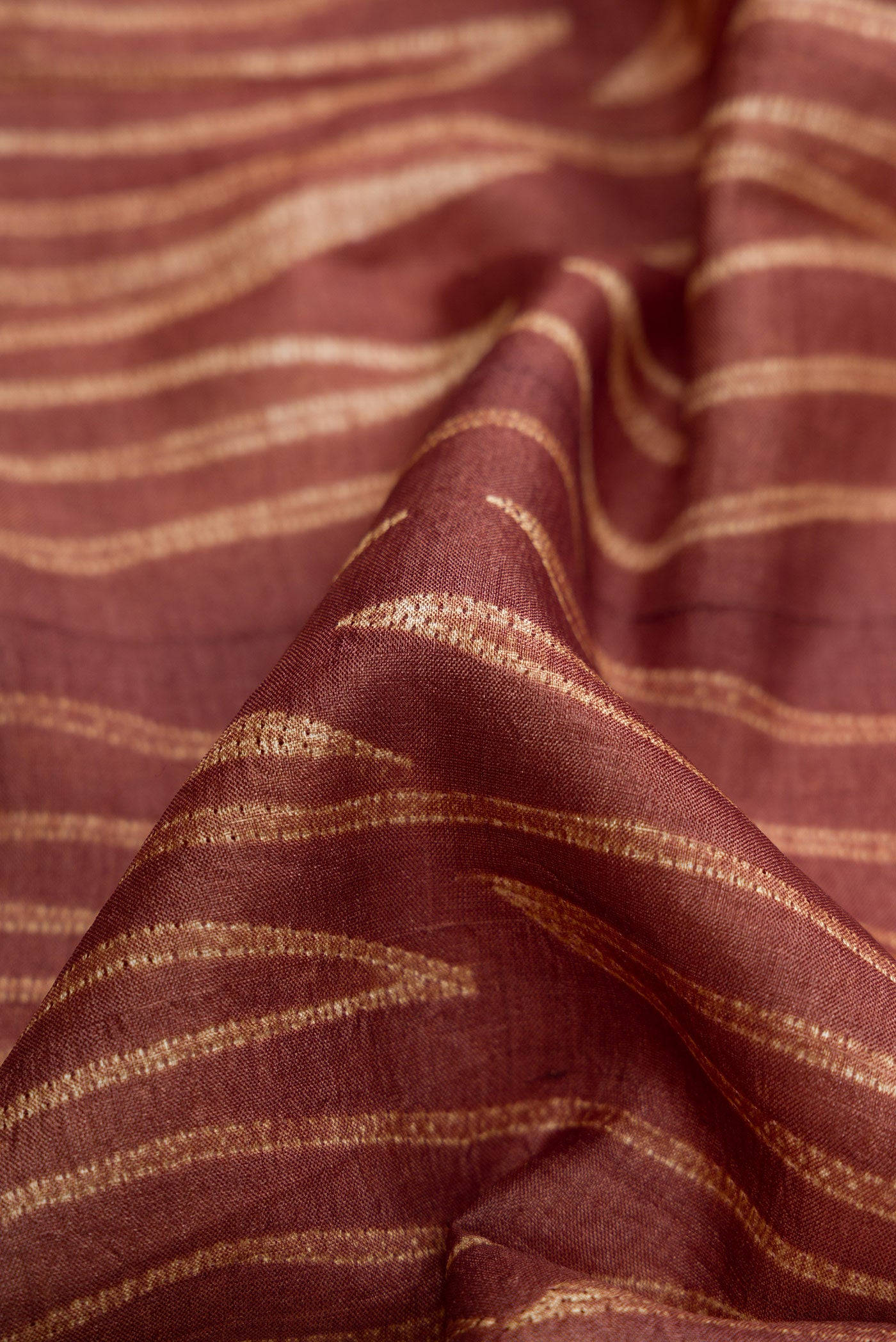 Close up of Brown Dual Tone Tussar Silk Saree with Printed design on the body and Printed Border.  displaying folds