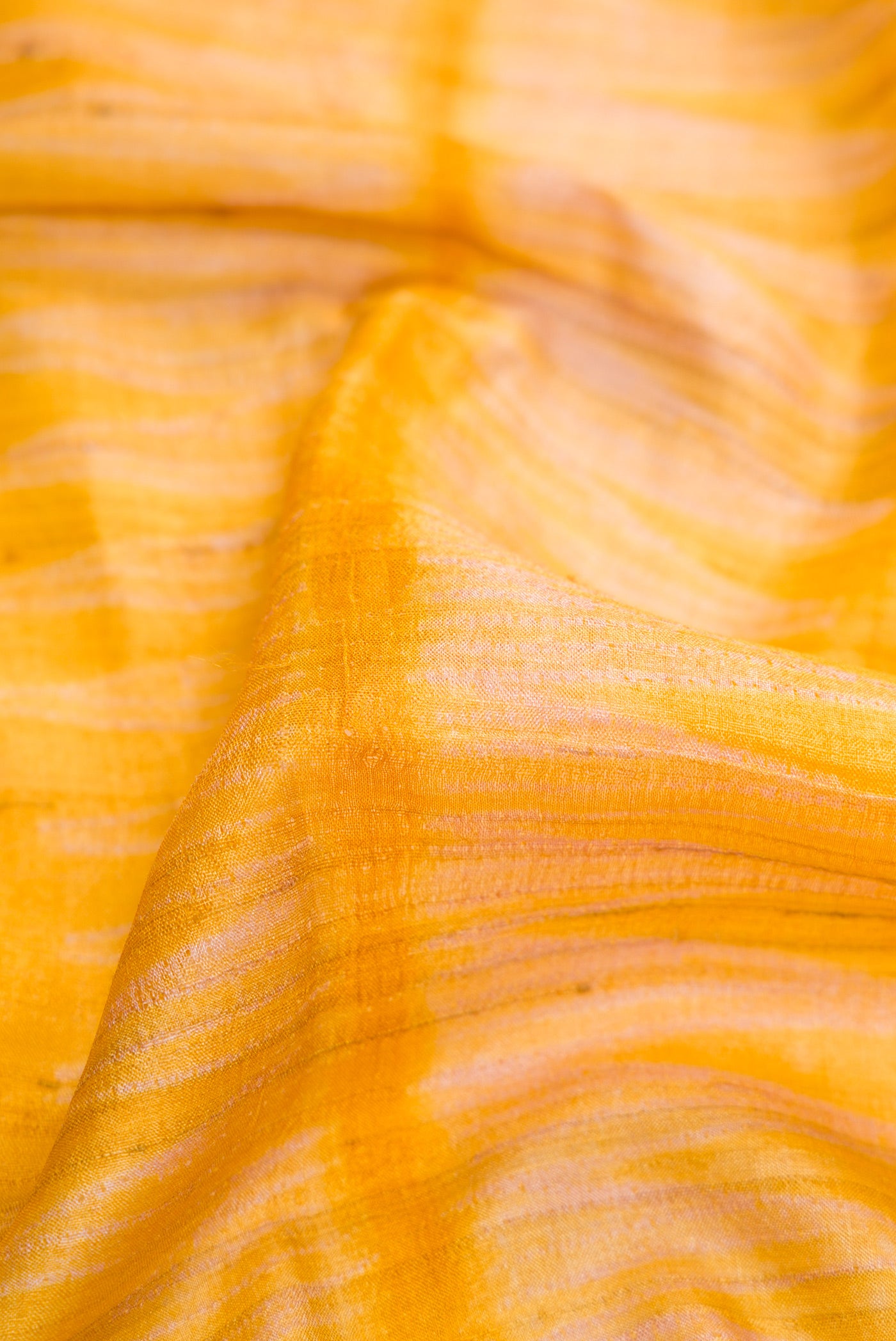 Close up of Mustard Dual Tone Tussar Silk Saree with Printed design on the body and Without Border.  displaying folds
