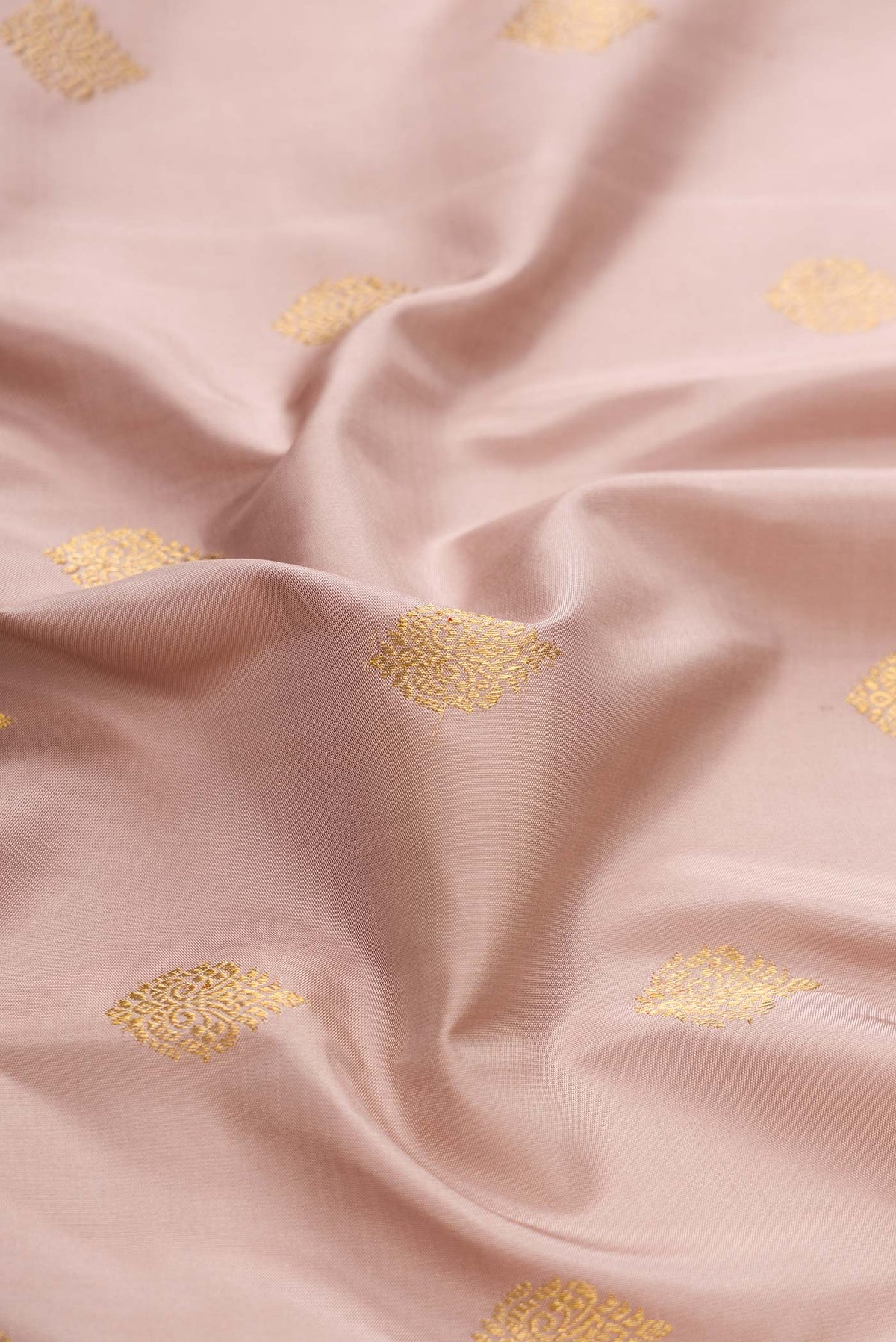 Close up of Pure Silk Pure Zari Rose Gold Dual Tone Kanchipuram Saree with Zari Butta on the body and Zari Border displaying folds