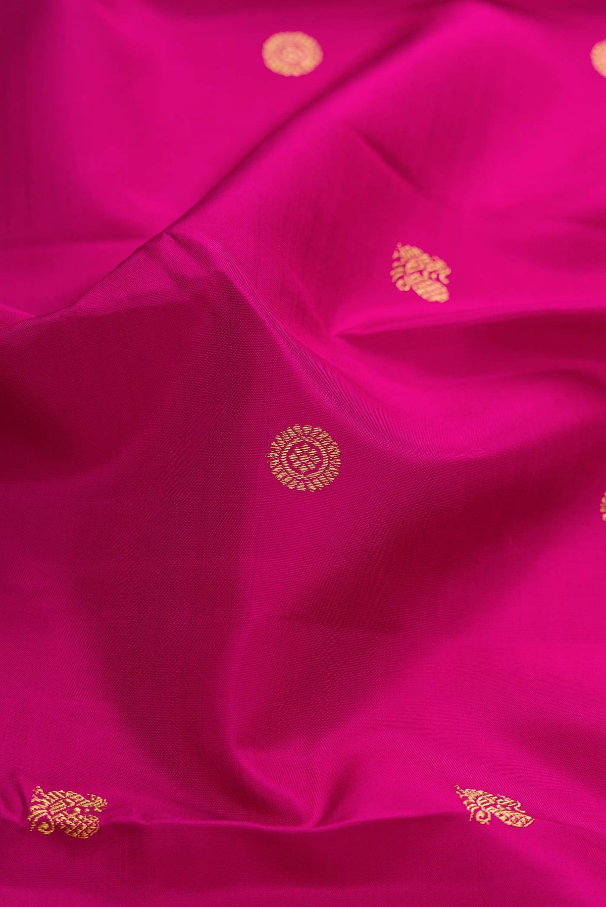 Close up of Pure Silk Pure Zari Magenta Dual Tone Kanchipuram Saree with Zari Butta on the body and Zari Border displaying folds